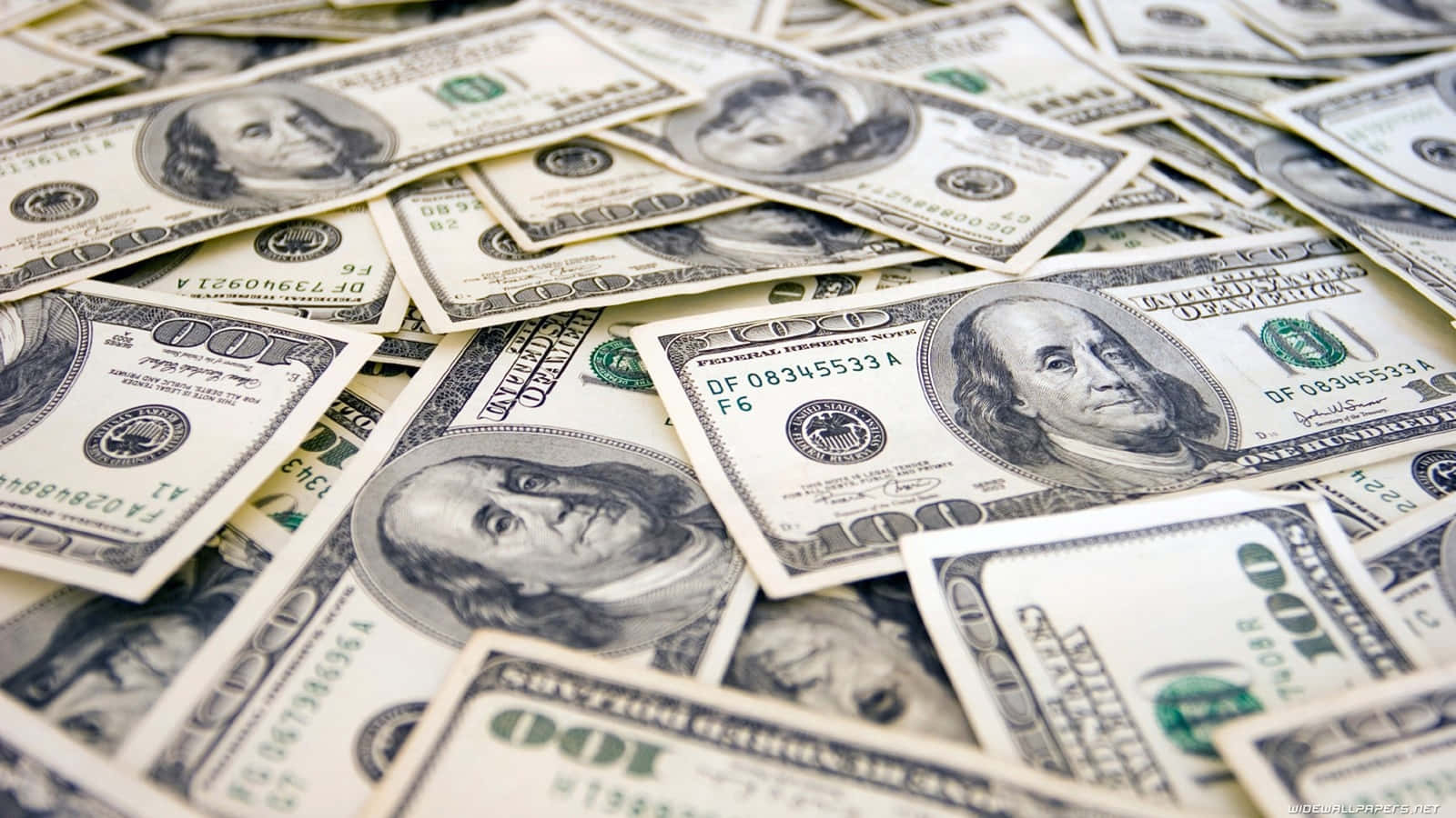 金錢 桌布 壁紙 — 一堆混亂的百元美鈔散落在表面上，焦點銳利地對準班傑明·富蘭克林的肖像。