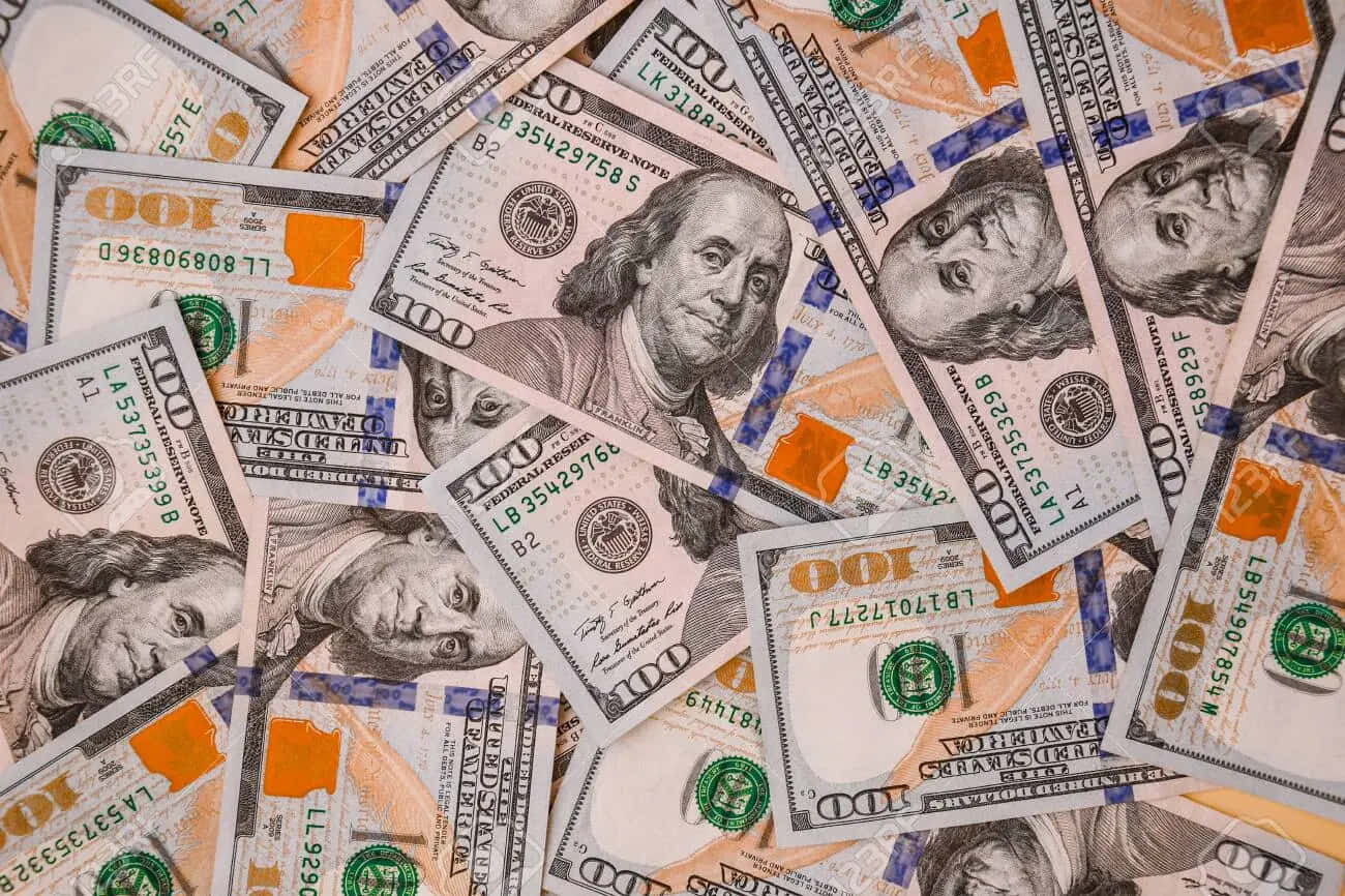 Money 桌布 壁紙 — 一堆混亂重疊的百元美鈔，上面有班傑明·富蘭克林的肖像和綠色橙色安全特徵。