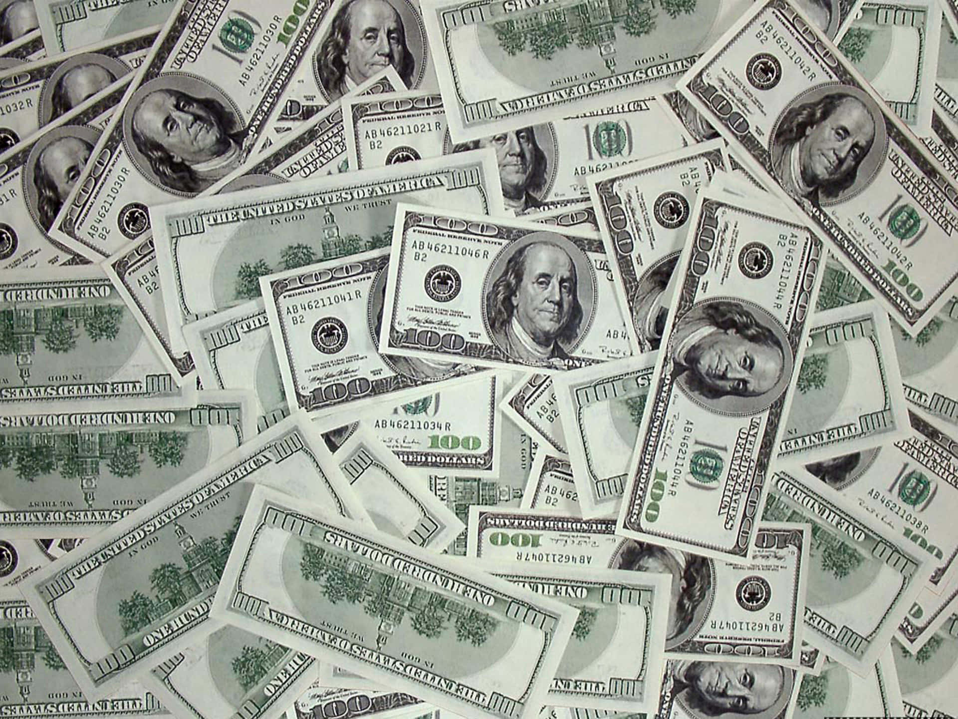 100 Dollar Bill 桌布 壁紙 — 一堆混亂重疊的百元美鈔，上面有班傑明·富蘭克林的肖像和綠色墨水細節。
