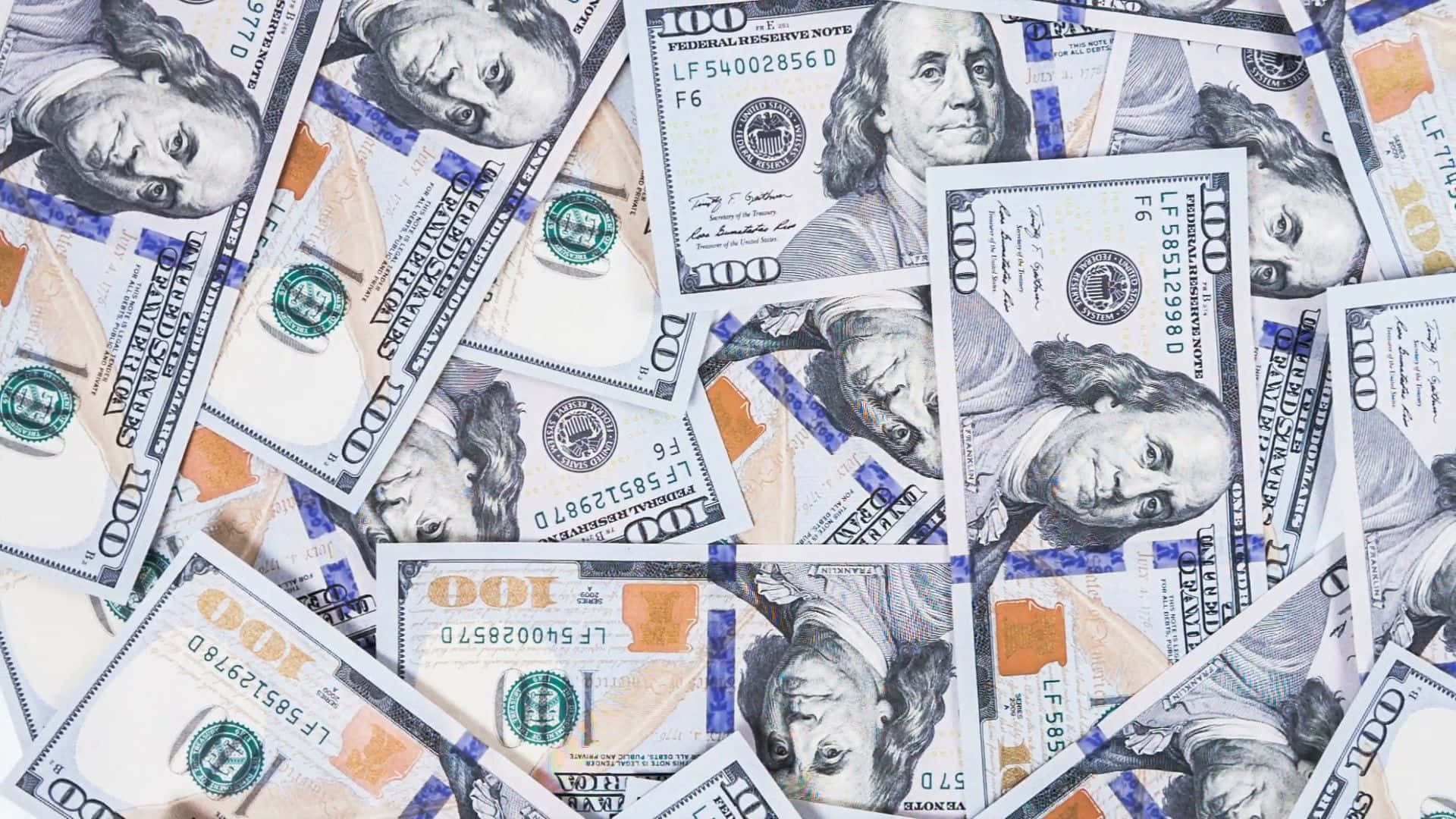 金錢 桌布 壁紙 — 一堆混亂重疊的百元美鈔，班傑明·富蘭克林的肖像朝上。