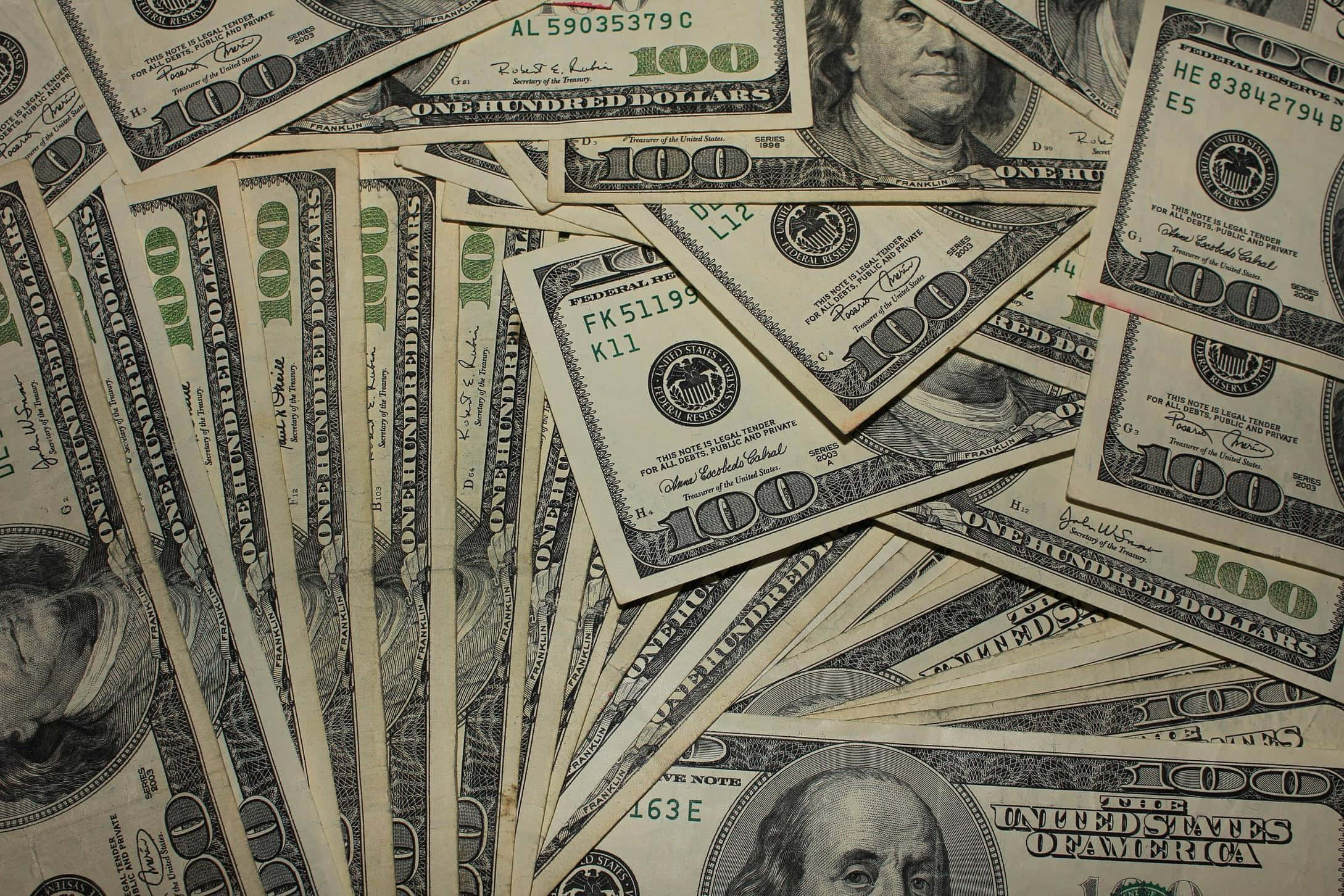 金錢 桌布 壁紙 — 一堆混亂重疊的百元美鈔散落在表面上。
