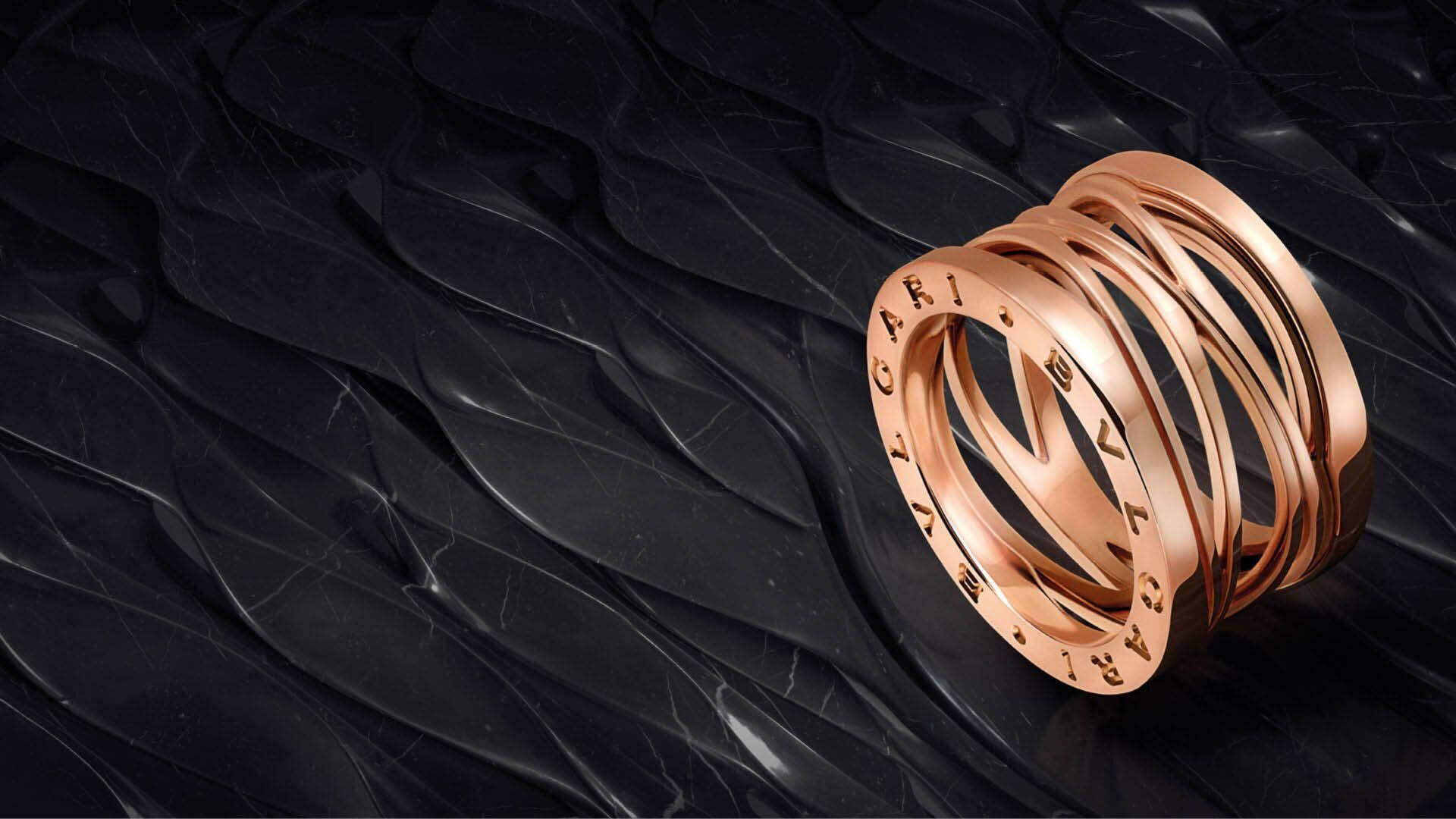 Bvlgari 桌布 壁紙 — 一堆玫瑰金Bvlgari戒指在帶有流動紋理的亮面黑色大理石表面上閃耀。
