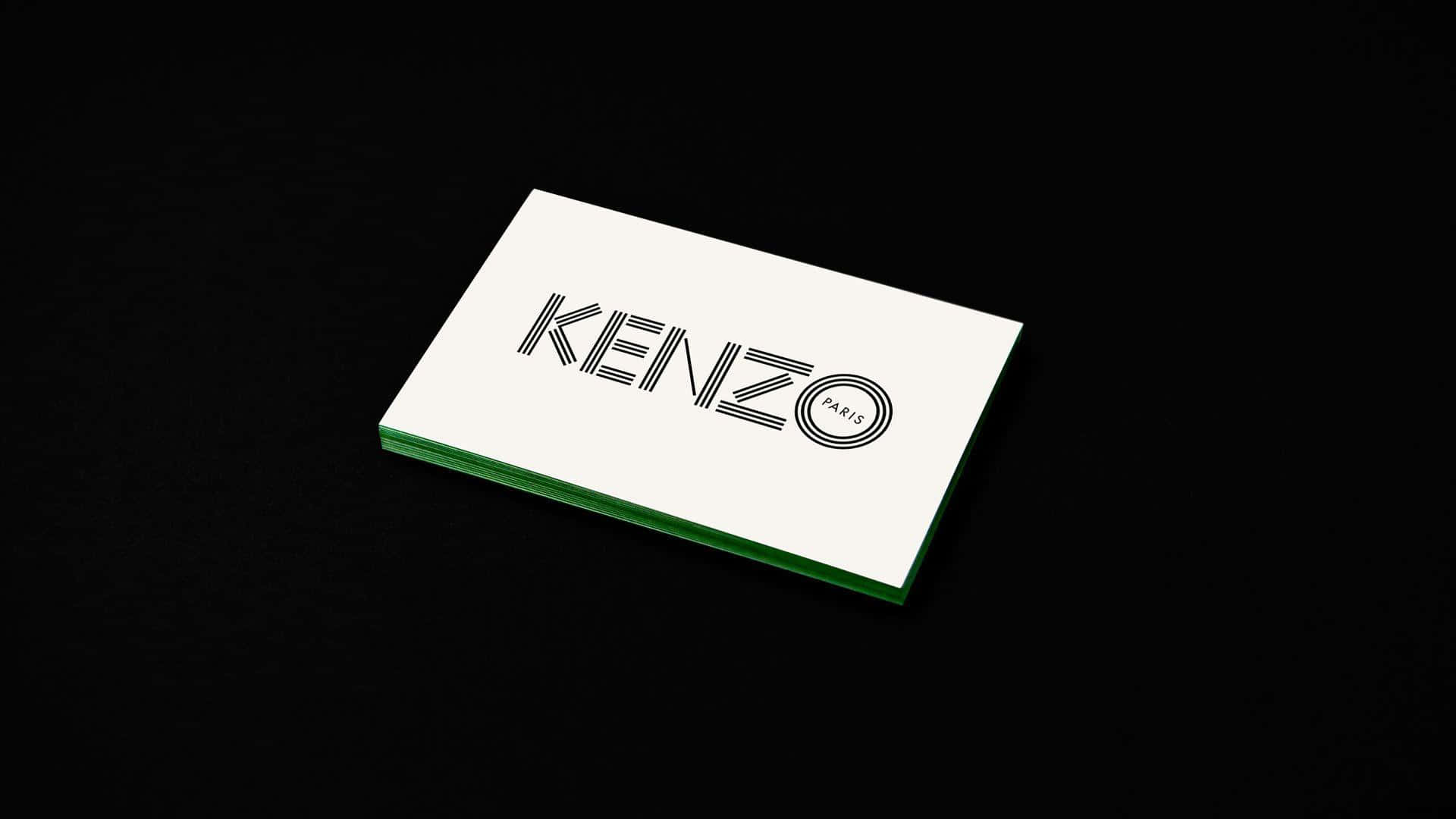 Designer Logo 桌布 壁紙 — 一堆白色名片，帶有綠色邊緣和黑色 Kenzo Paris 標誌，放置在黑色紋理表面上。