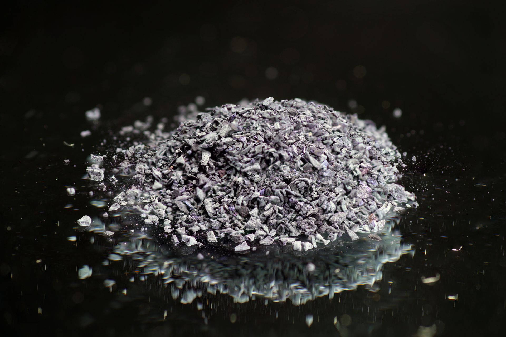 Material 桌布 壁紙 — 一堆破碎的紫色玻璃碎片在黑色反光表面上聚焦光線下閃爍。
