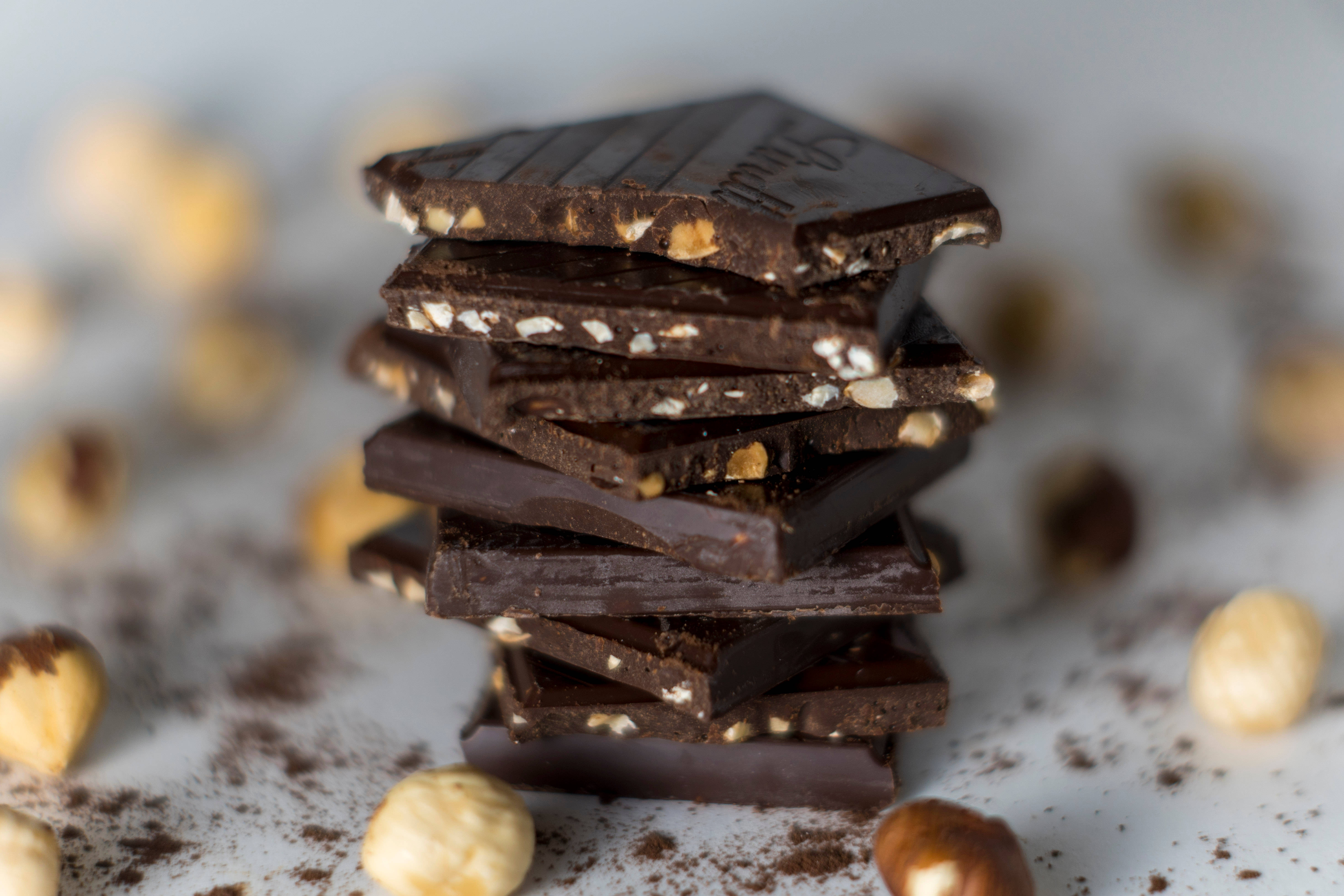 Chocolate 桌布 壁紙 — 一堆碎黑巧克力條，配以榛子和可可粉，置於白色表面上。
