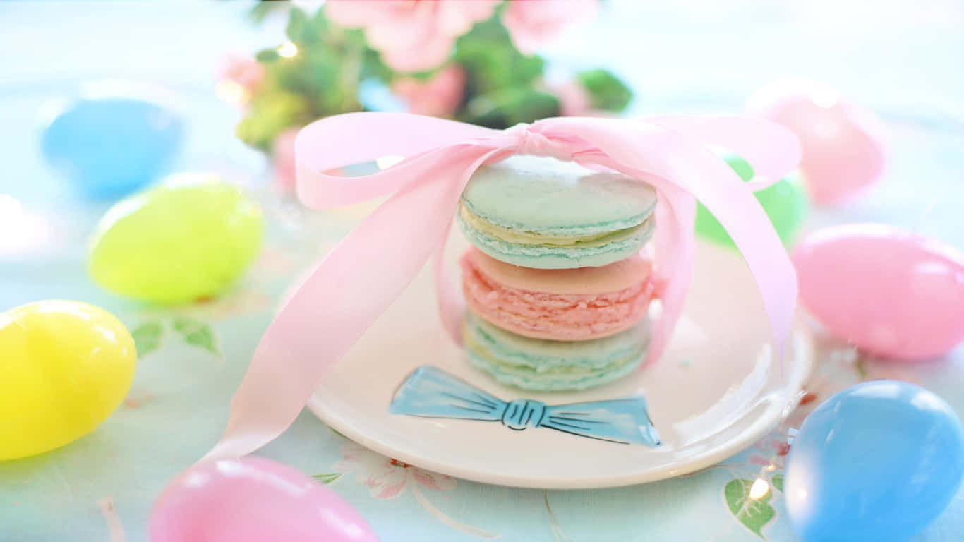 1366x768 Pastries 桌布 壁紙 — 一堆粉彩馬卡龍用粉紅色絲帶綁著，放在一個盤子上，周圍環繞著色彩繽紛的復活節彩蛋和花朵。