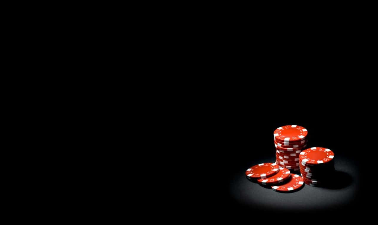 Casino 桌布 壁紙 — 一堆紅色籌碼在聚光燈下於漆黑背景中發光。
