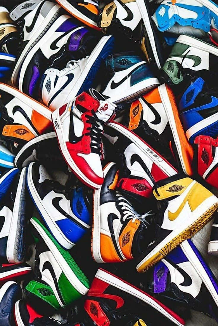 球鞋 桌布 壁紙 — 一堆色彩繽紛、充滿活力的Nike Air Jordan運動鞋，以各種大膽色調和經典設計雜亂地堆疊在一起。