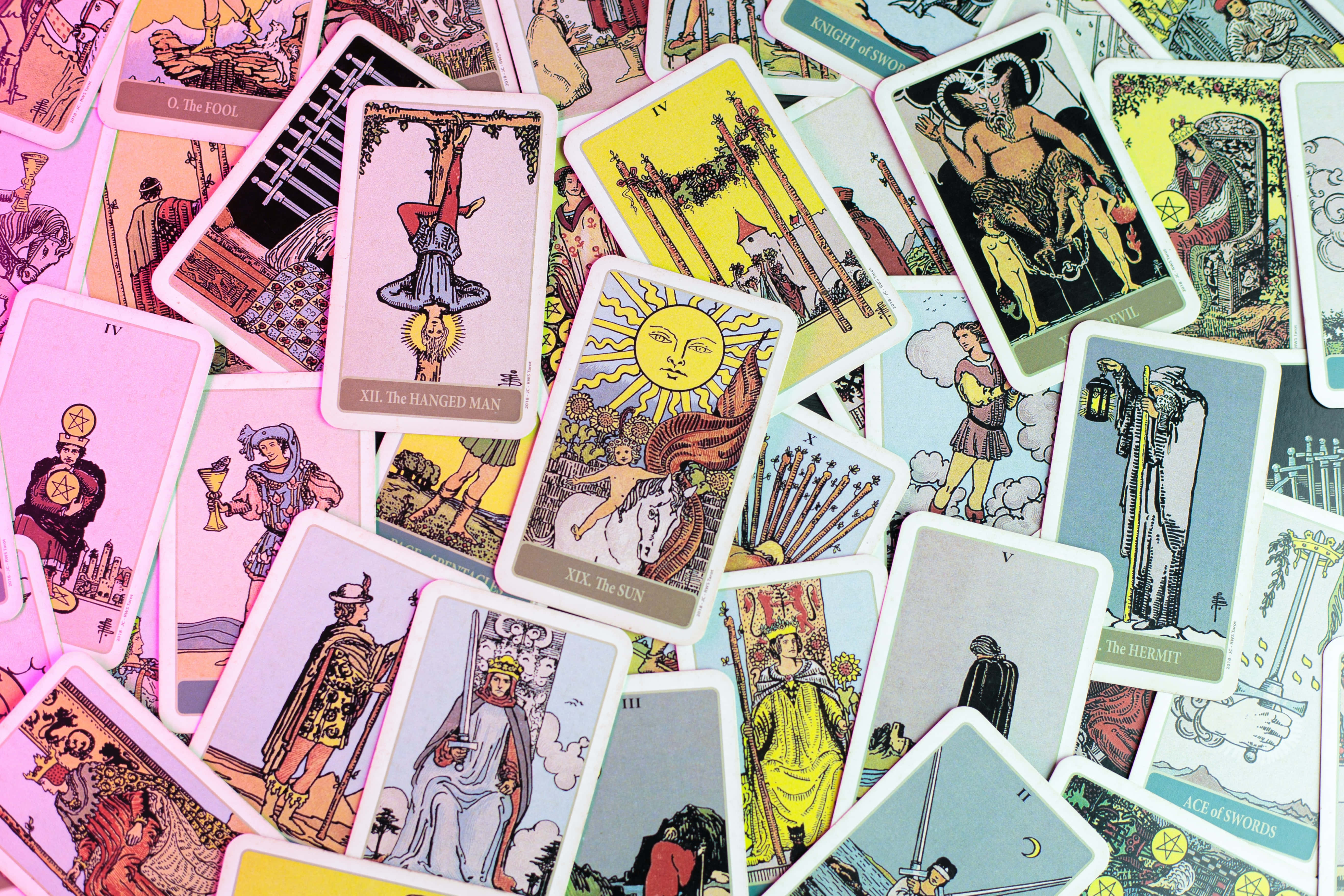 Tarot Card 桌布 壁紙 — 一堆色彩繽紛、散落的插圖塔羅牌，描繪神秘人物和象徵性圖案，色彩豐富。