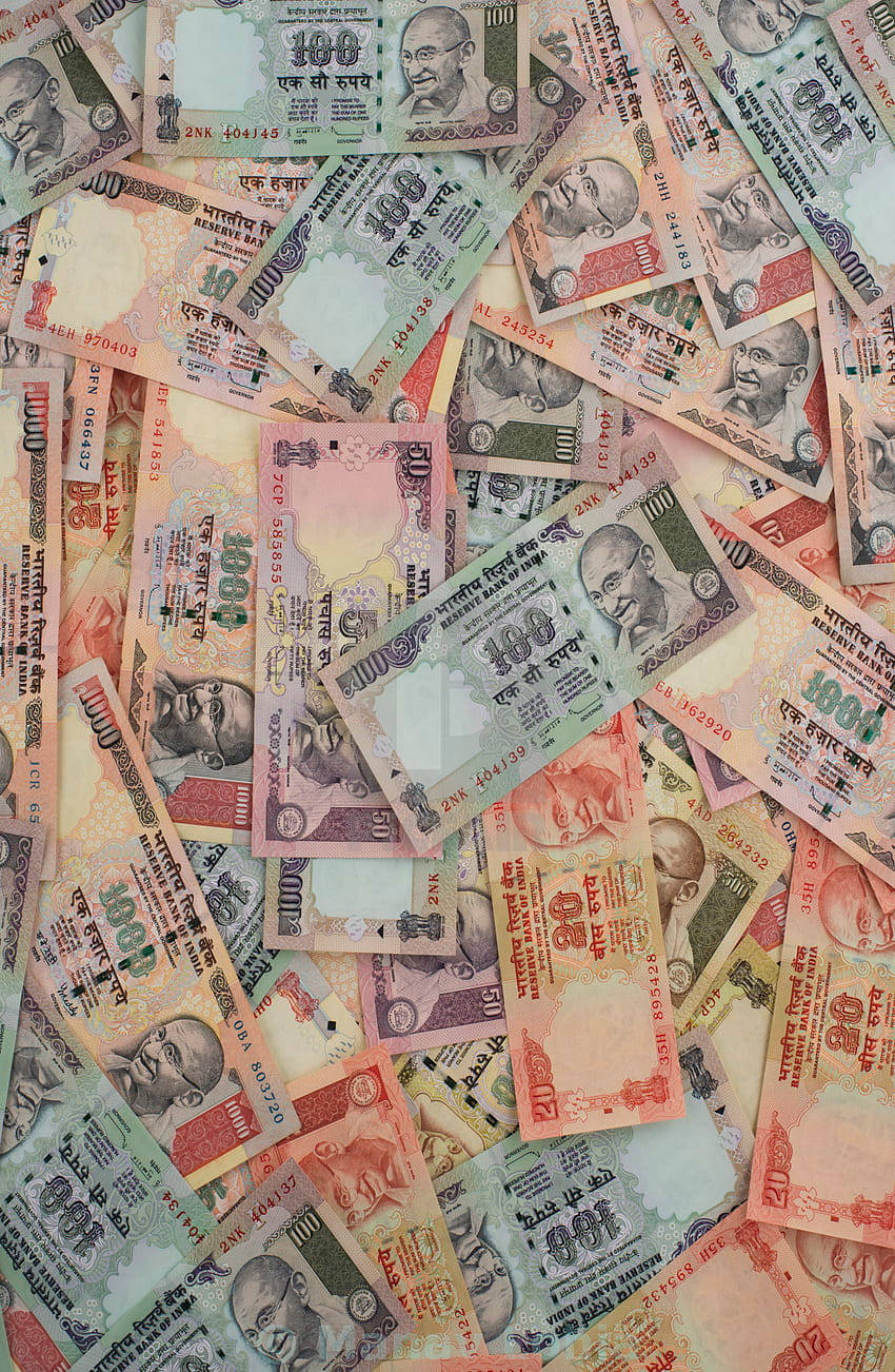 金錢 桌布 壁紙 — 一堆色彩繽紛、雜亂無章的印度盧比紙幣，上面印有不同面額和顏色的聖雄甘地肖像。