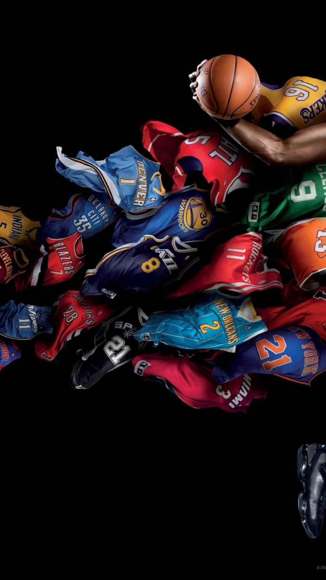 一名籃球運動員的手在NBA球衣堆上方握住球。