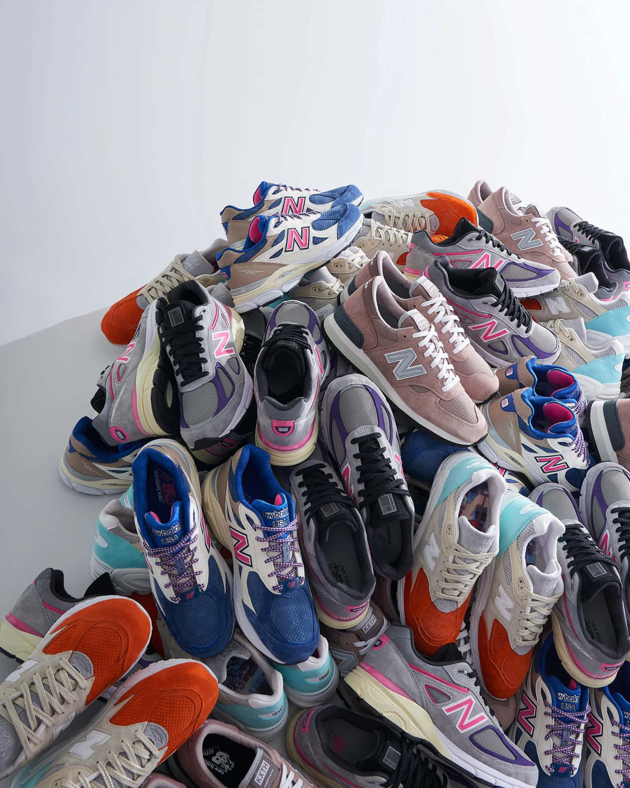 New Balance 桌布 壁紙 — 一堆色彩繽紛的New Balance運動鞋堆疊在純白色背景上。
