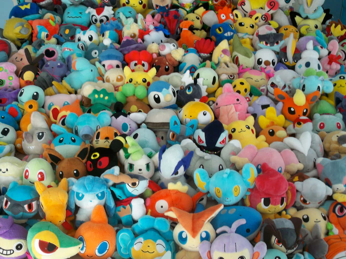 Pokemon Toys 桌布 壁紙 — 一堆色彩繽紛的寶可夢毛絨玩具，充滿活力且雜亂無章，質地柔軟，表情豐富。
