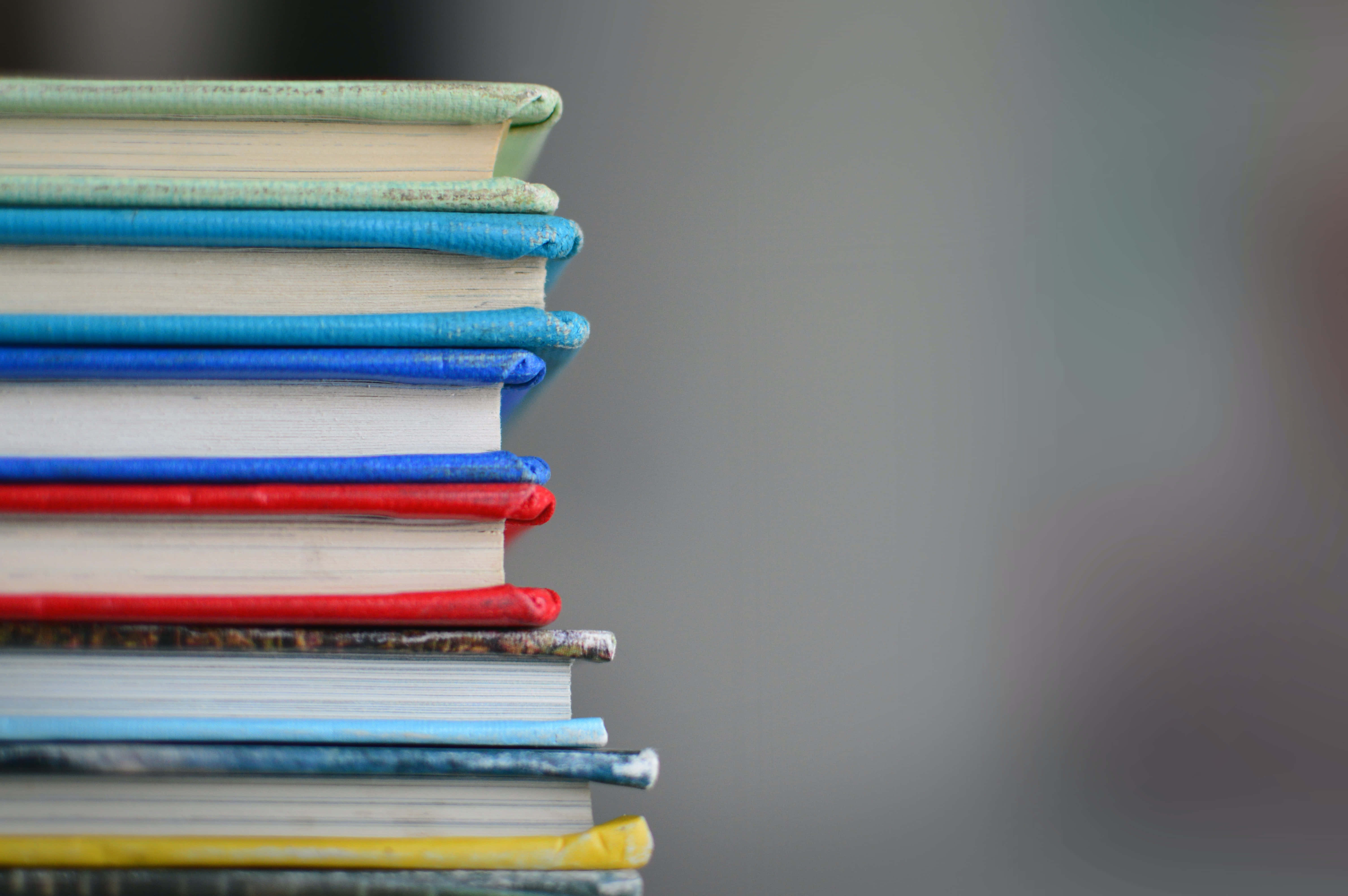 Educational 桌布 壁紙 — 一堆色彩繽紛的復古書籍特寫，書脊帶有紋理，背景柔和模糊。