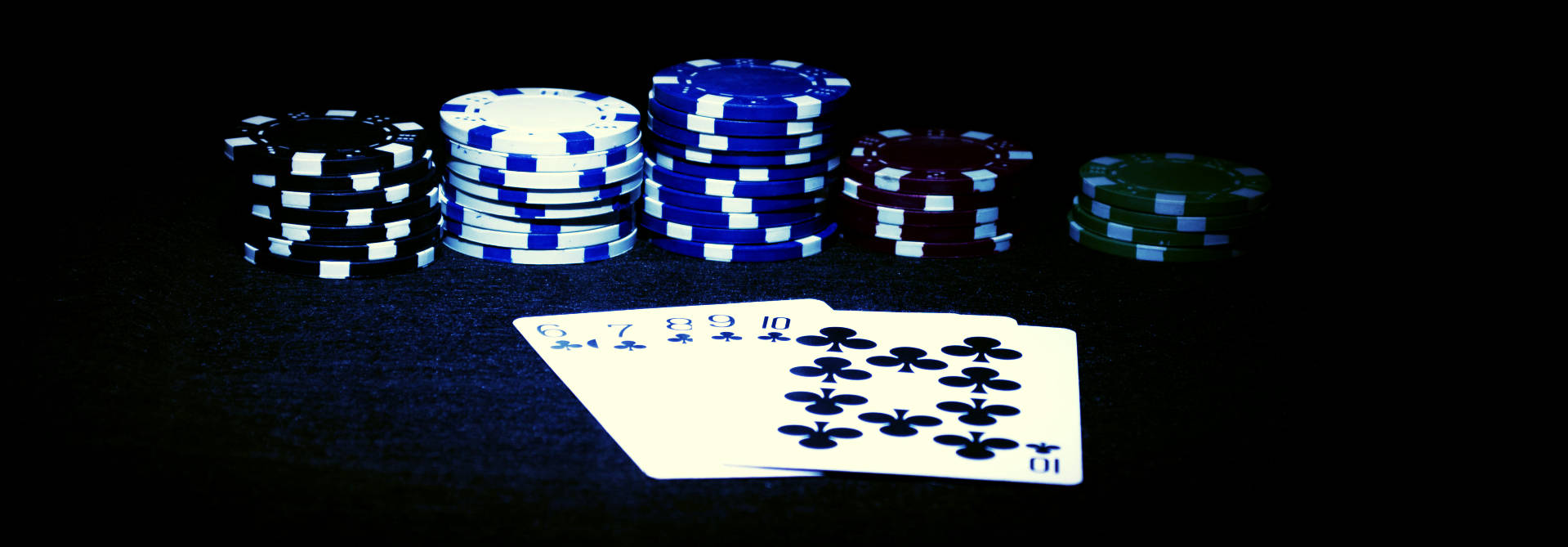 Cards 桌布 壁紙 — 一堆色彩繽紛的撲克籌碼和扇形的撲克牌在戲劇性燈光下在深色氈面上發光。