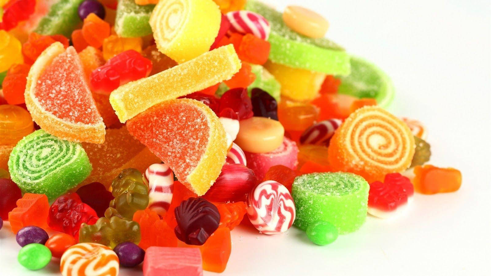 糖果 桌布 壁紙 — 一堆色彩繽紛的糖果，包括小熊軟糖、螺旋形和柑橘片，放在潔白的背景上。