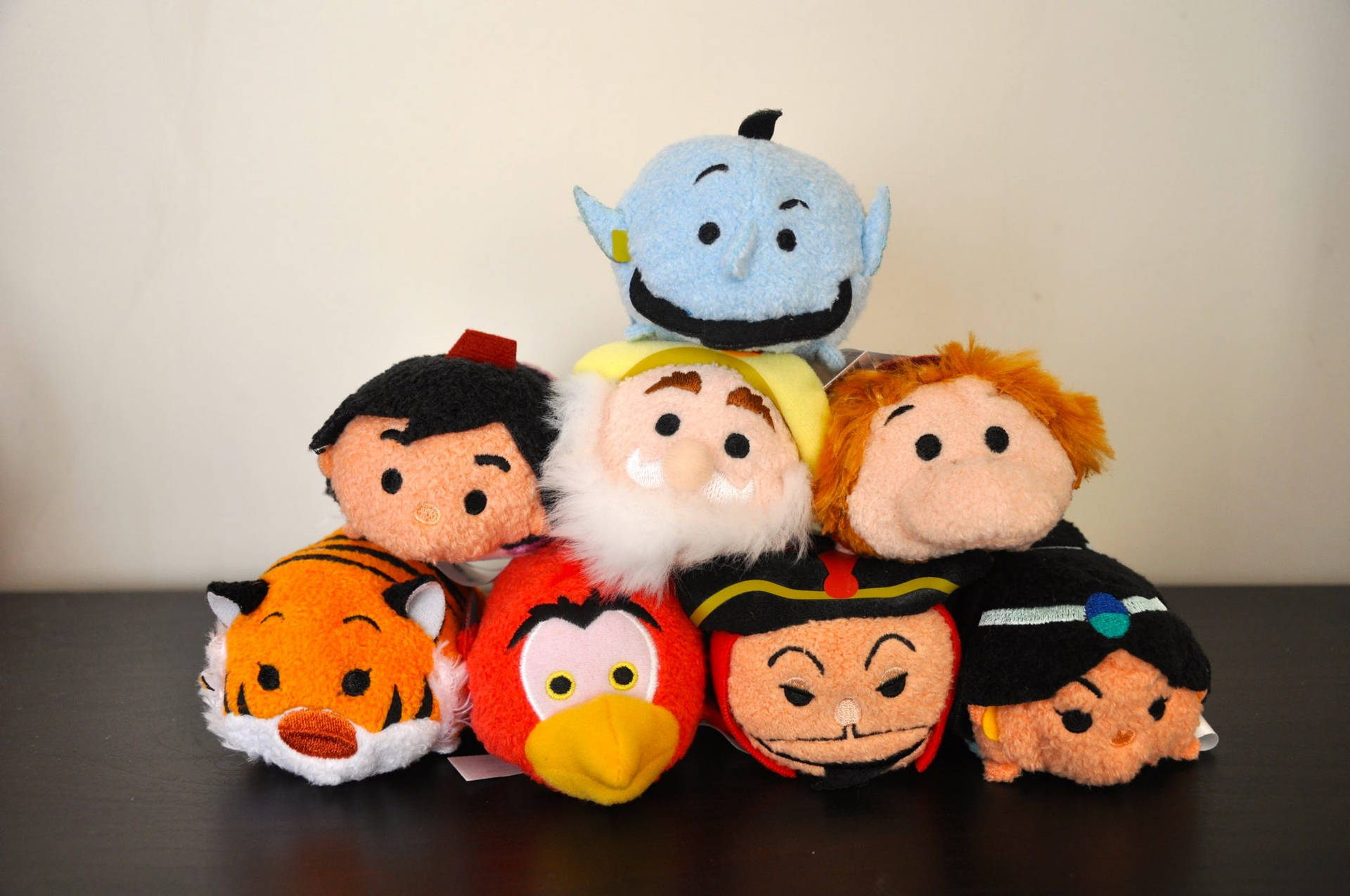 深色桌子上的迪士尼 Tsum Tsum 絨毛玩具收藏，包括阿拉丁、精靈和阿布。 — Tsum tsum 壁紙
