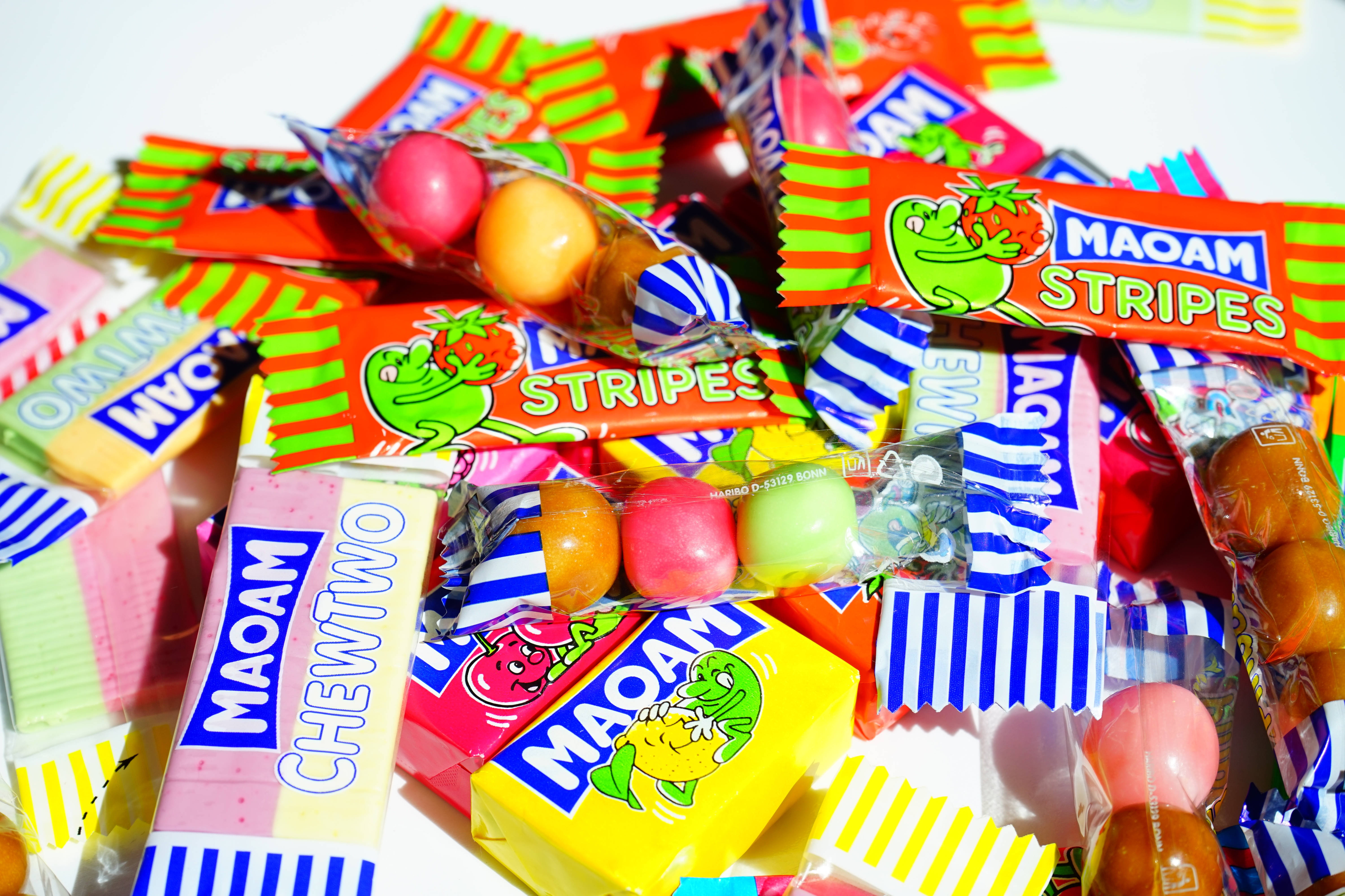 chewy 桌布 壁紙 — 一堆色彩鮮豔的Maoam糖果棒和各式糖果，包裝明亮。
