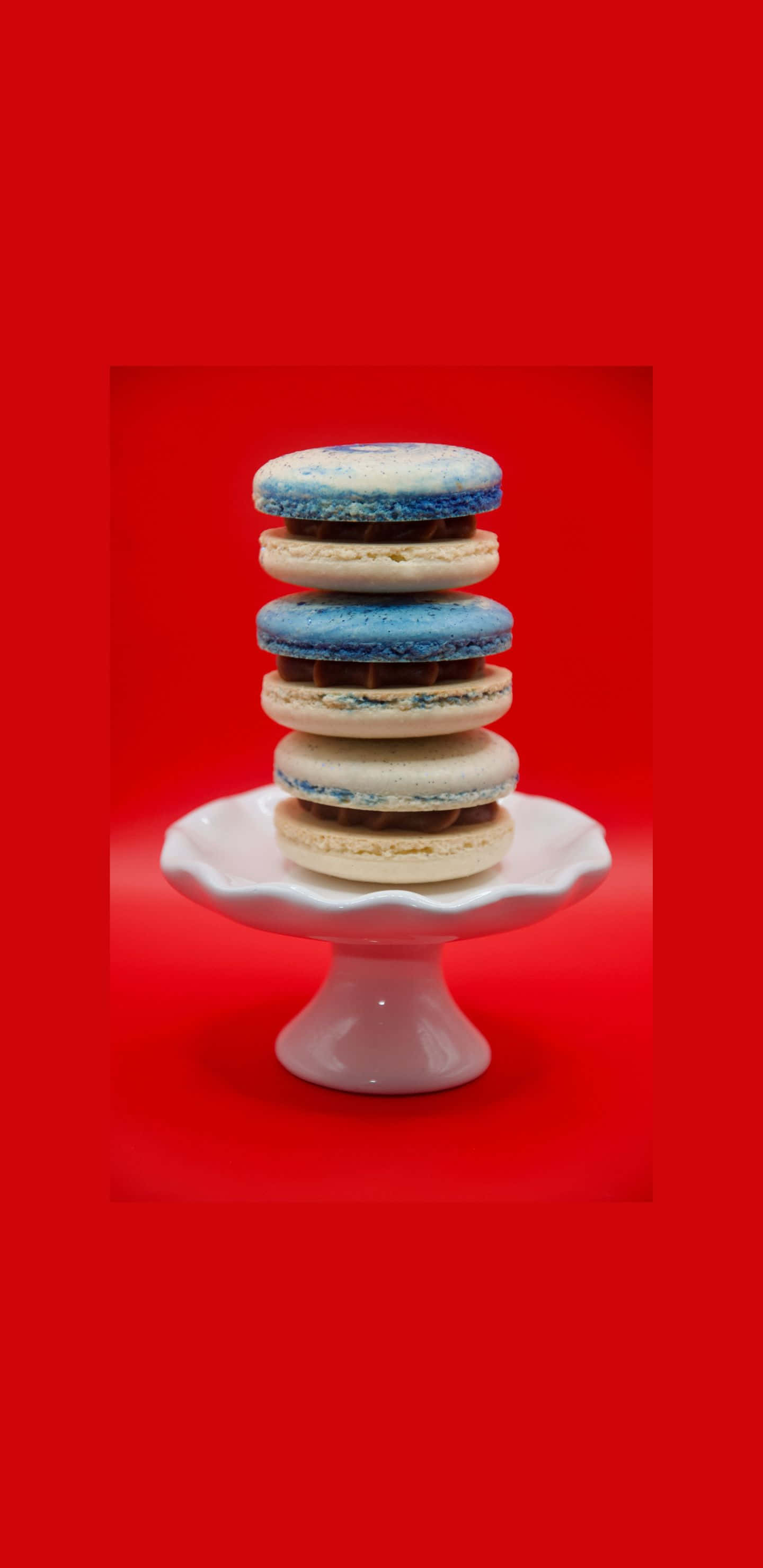 Pixel 3xl Cookies 桌布 壁紙 — 一堆藍白馬卡龍優雅地放在白色蛋糕架上，背景是鮮明的紅色。