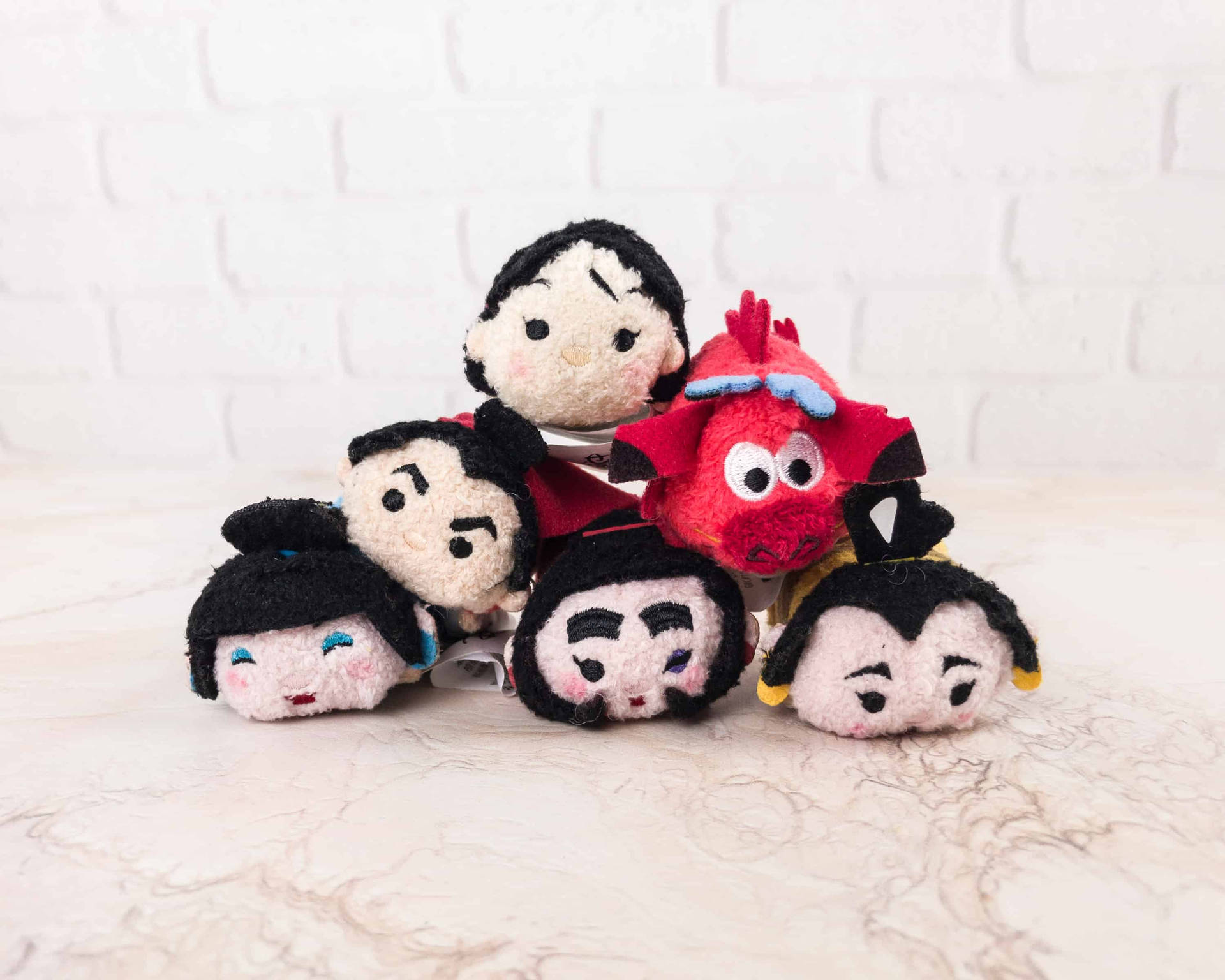 一組迪士尼 Tsum Tsum 毛絨玩具放在大理石上，背景為白色磚牆。 — Tsum tsum 壁紙