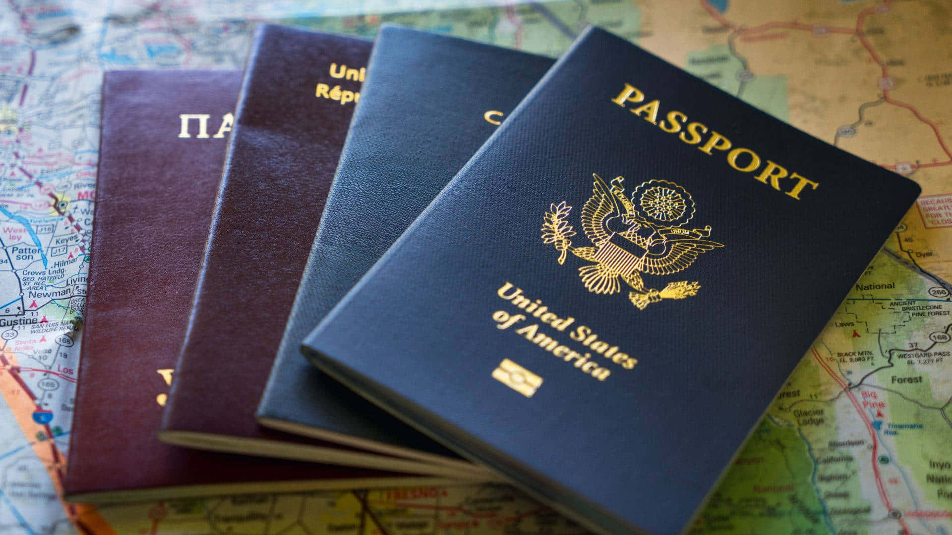 Passport 桌布 壁紙 — 一堆護照，包括一本美國護照，放在色彩繽紛的世界地圖上。