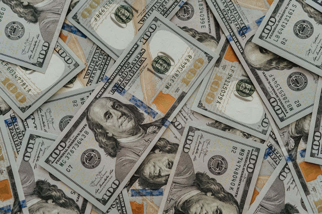 金錢 桌布 壁紙 — 一堆重疊的一百美元鈔票雜亂地堆疊，形成了綠色和橙色的紋理表面。