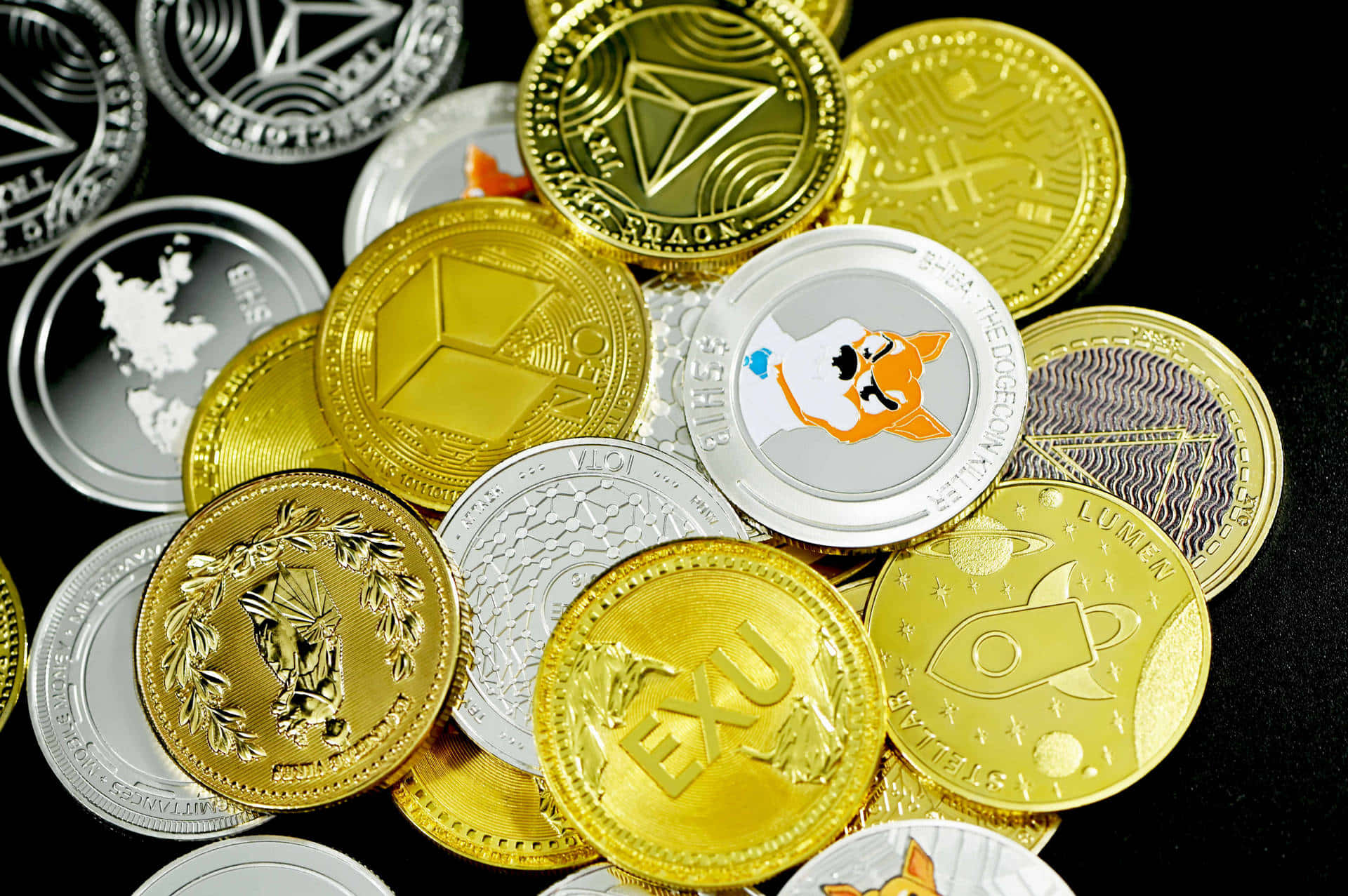 金錢 桌布 壁紙 — 一堆閃亮的金銀加密貨幣硬幣，帶有獨特標誌，散落在深色表面上。