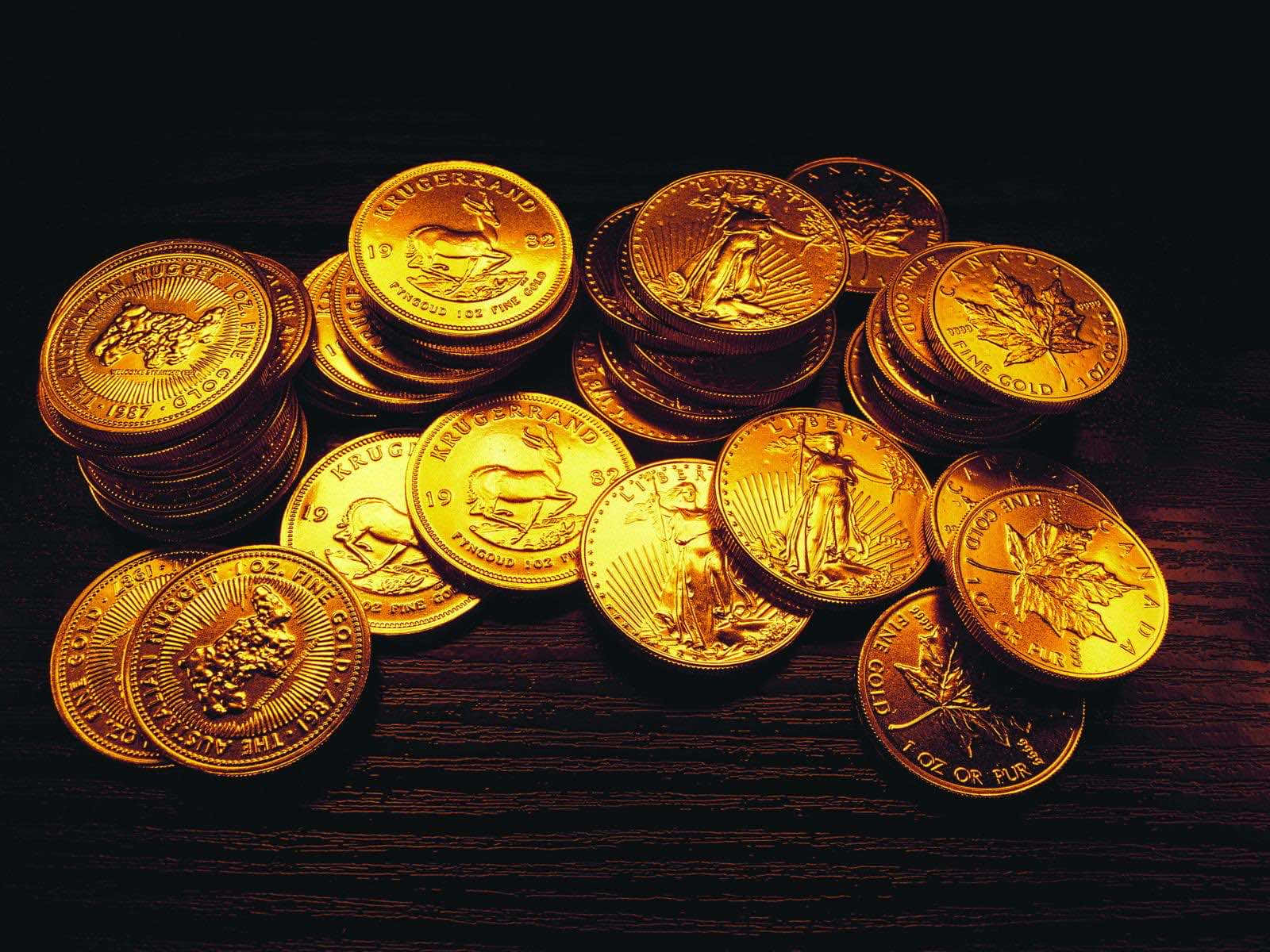 金錢 桌布 壁紙 — 一堆閃閃發光的金幣，帶有精細雕刻，放在溫暖燈光下的深色木質表面上。