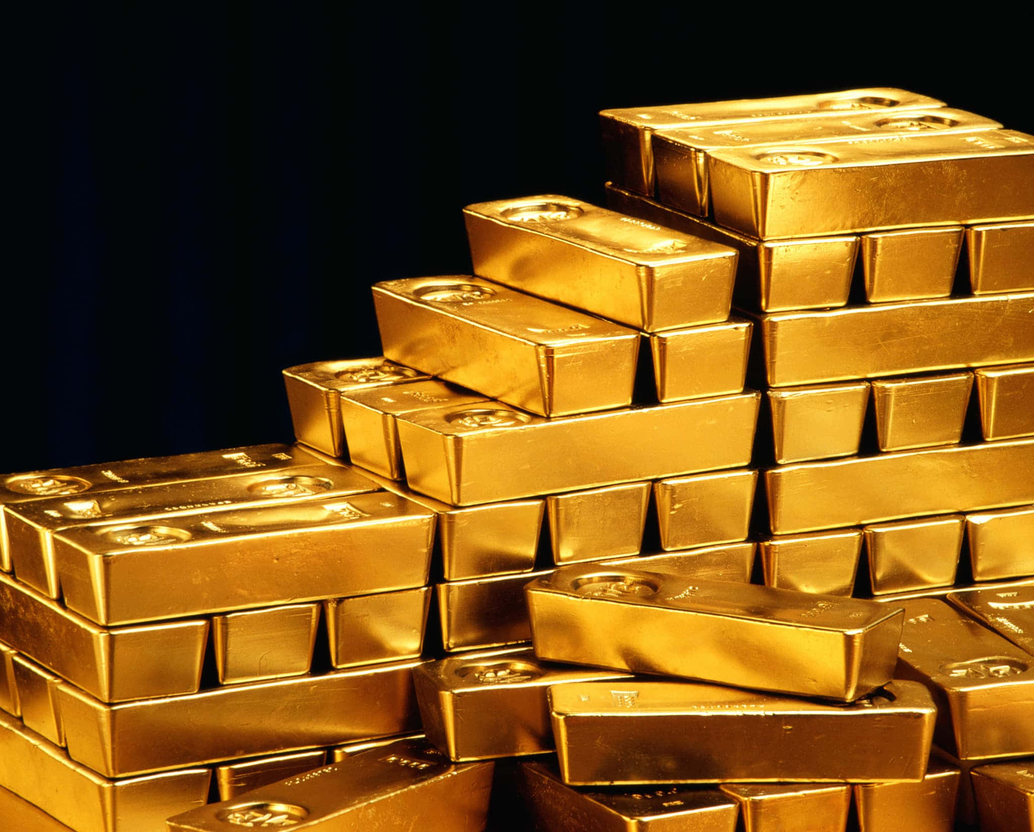 金色動態 桌布 壁紙 — 一堆閃閃發光的金條以金字塔形排列在深色背景上。