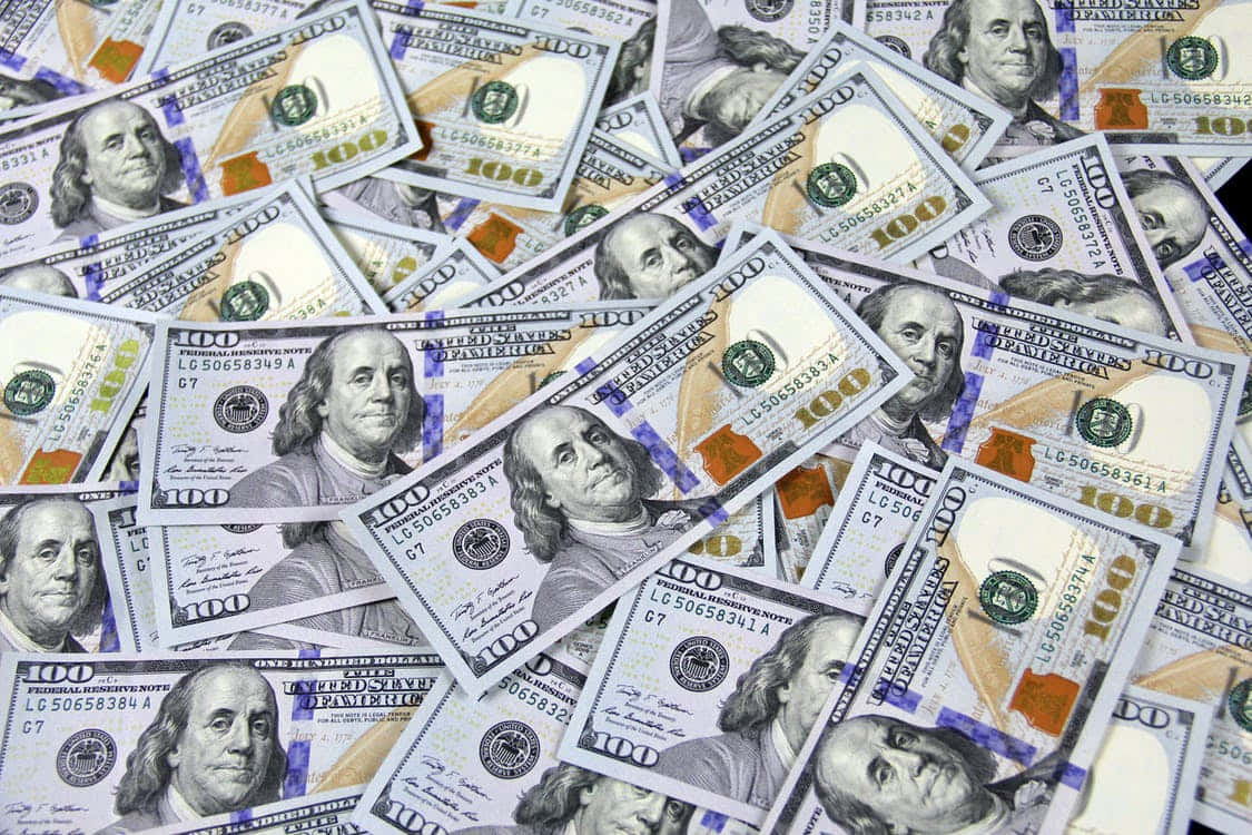 Money 桌布 壁紙 — 一堆雜亂重疊的百元美鈔，上面有班傑明·富蘭克林的肖像和綠色墨水細節。