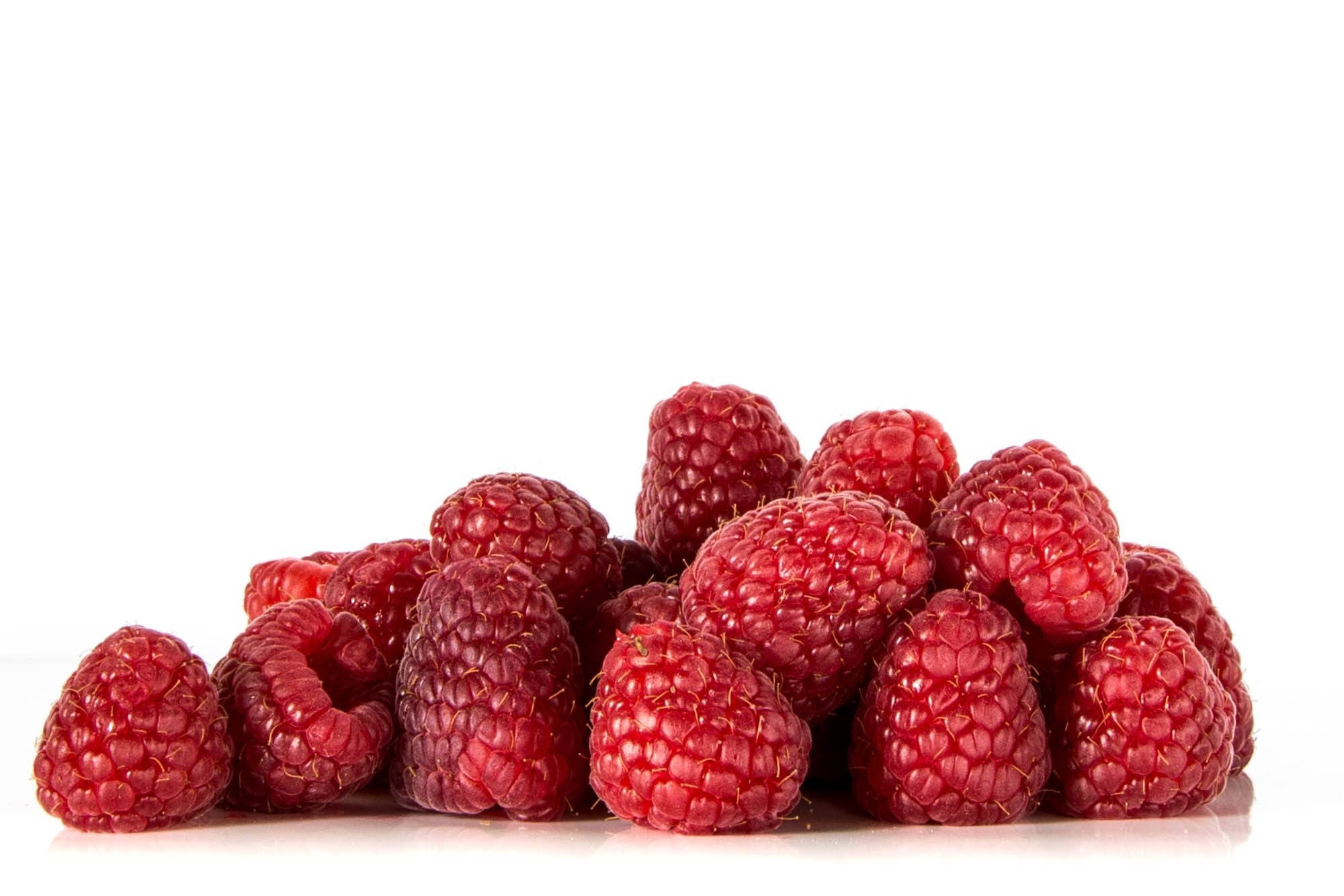 Berry 桌布 壁紙 — 一堆飽滿的紅覆盆子閃耀在純白背景上，帶有柔和陰影。