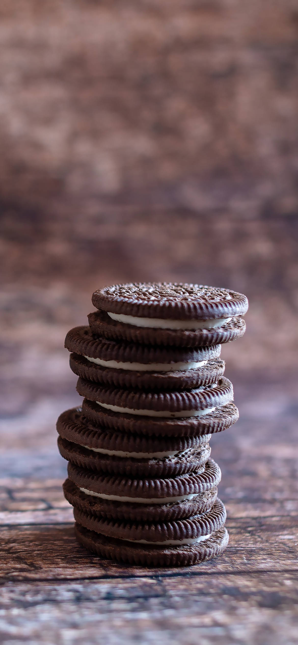 Cookie 桌布 壁紙 — 一堆高高的巧克力夾心餅乾，內有奶油餡料，放在質樸的木質表面上，背景是模糊的棕色。