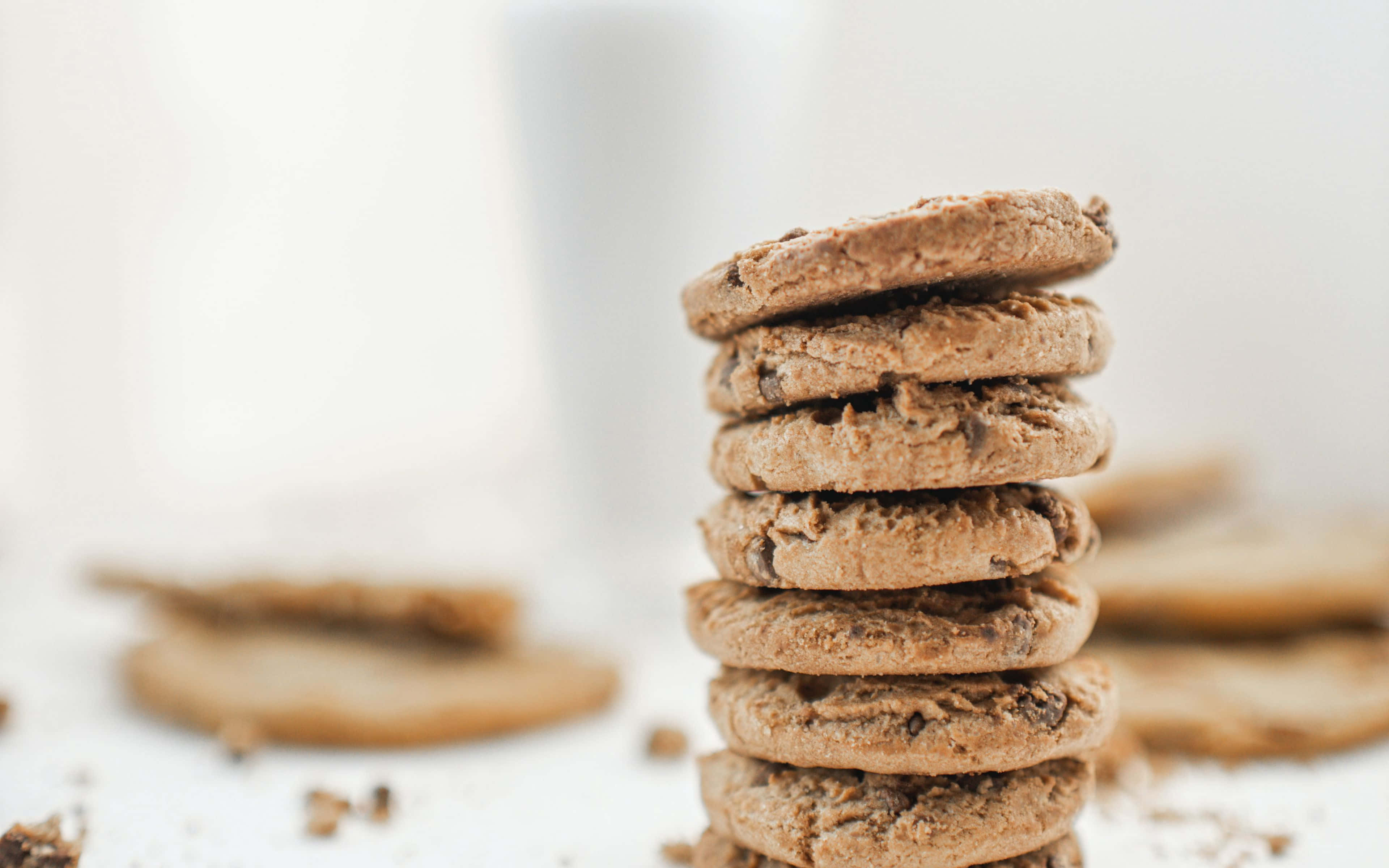 Cookies 桌布 壁紙 — 一堆高高的巧克力餅乾，在明亮的白色表面上散落著碎屑。