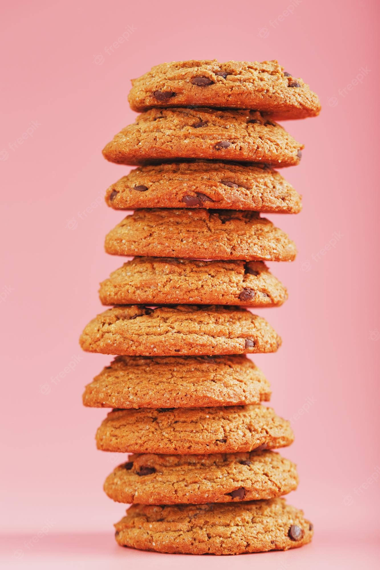 Cookie 桌布 壁紙 — 一堆高高的金黃色巧克力餅乾放在柔和的粉紅色背景上。