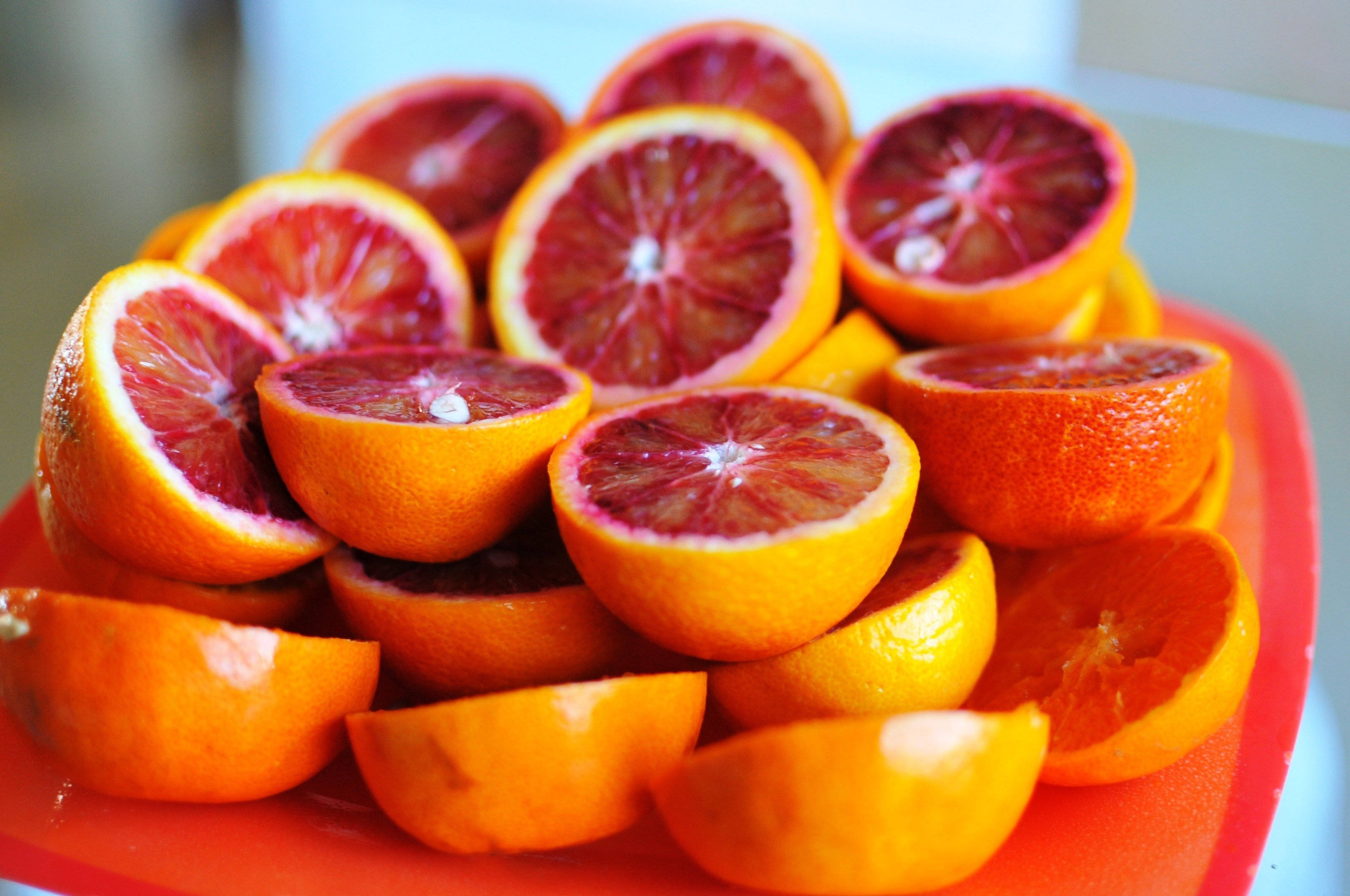Blood Orange 桌布 壁紙 — 一堆鮮切的血橙片，在亮紅色盤子上露出深紅色的果肉。