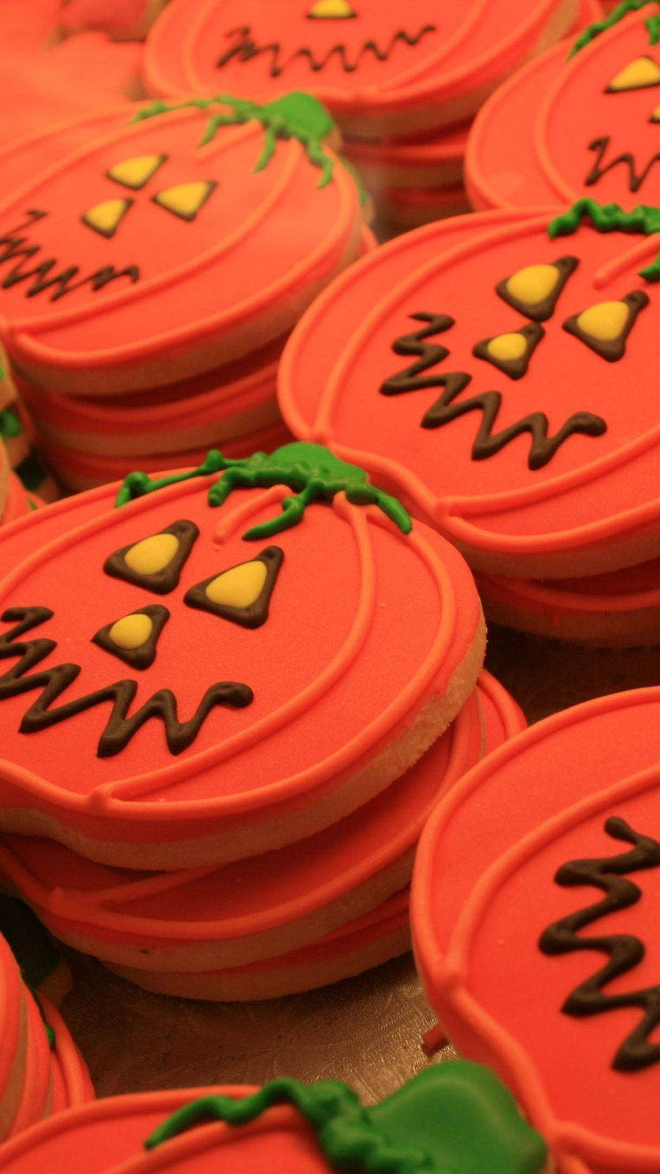 Cookie 桌布 壁紙 — 一堆鮮橙色南瓜形狀的餅乾，帶有巧克力南瓜燈臉和綠色莖。