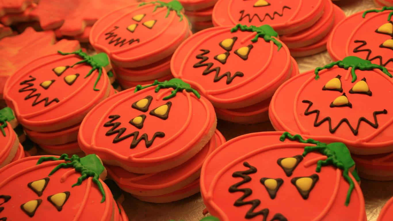 1366x768 Desserts 桌布 壁紙 — 一堆鮮橙色南瓜形狀的餅乾，帶有詭異的傑克南瓜燈臉孔和綠色莖部。