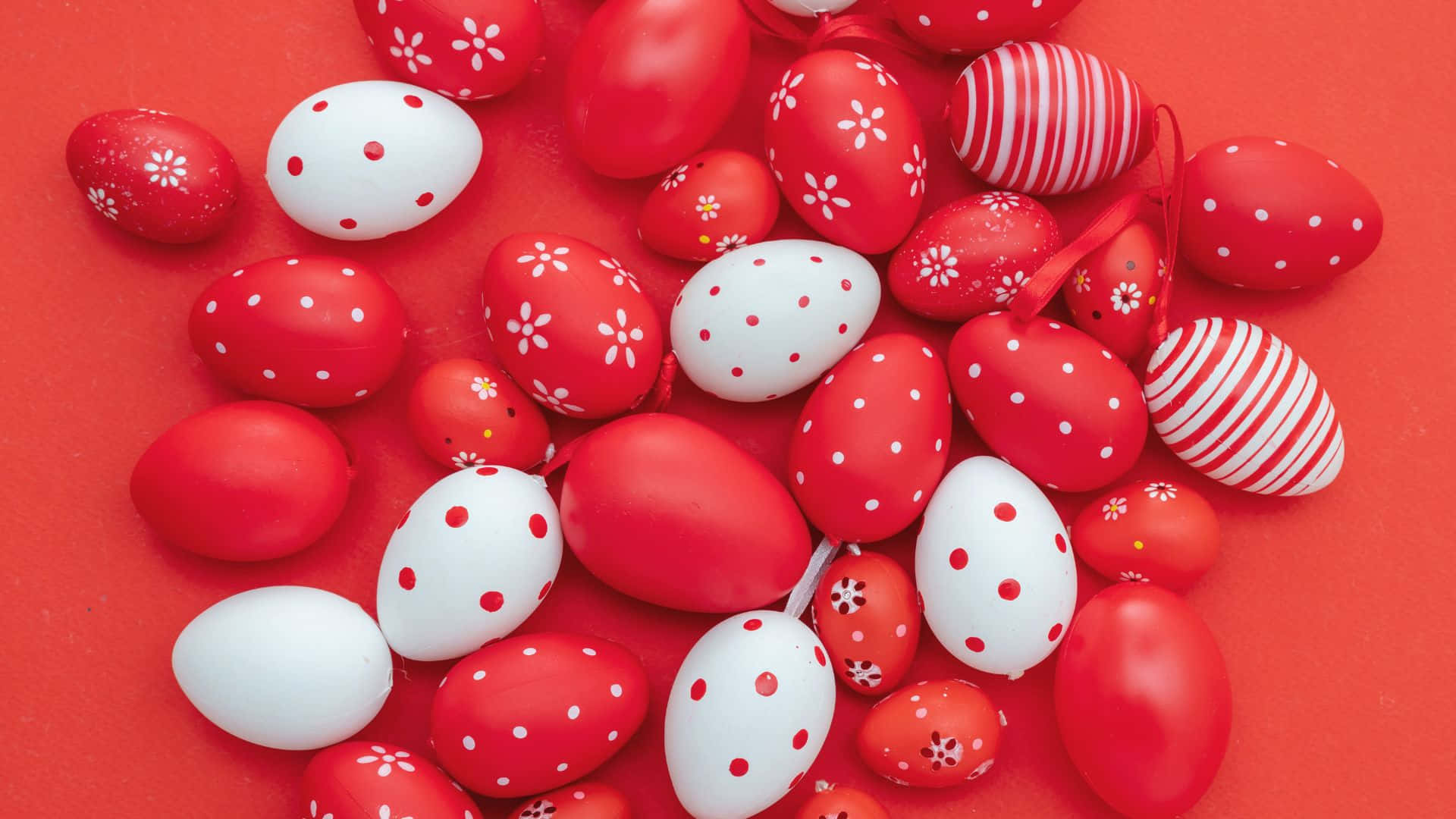 Eggs 桌布 壁紙 — 一堆鮮豔的紅白裝飾復活節蛋，帶有花卉和條紋圖案，置於純紅色背景上。