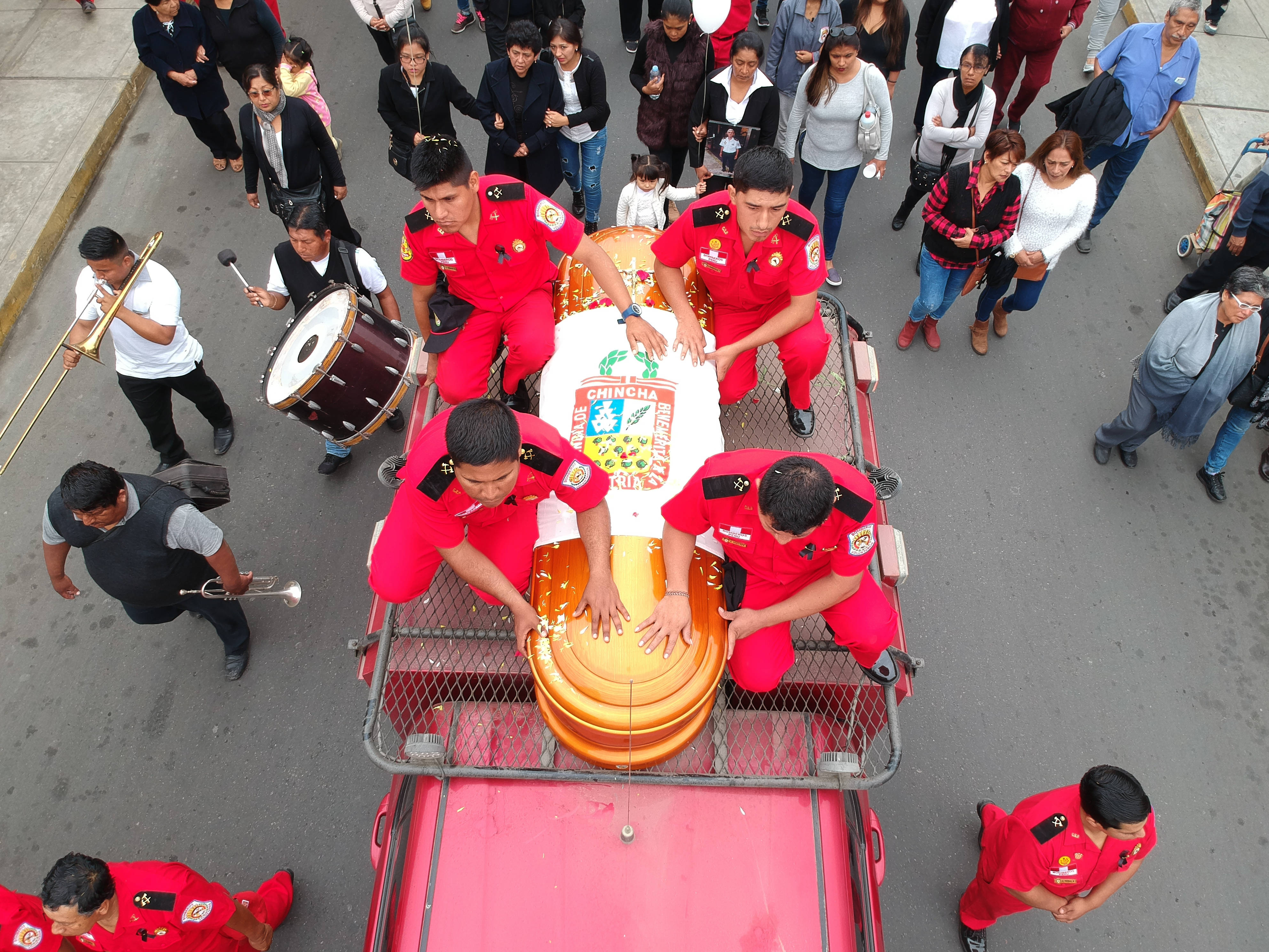 Funeral 桌布 壁紙 — 一場充滿活力的街頭遊行，身穿制服的音樂家和舞者在一輛粉紅色卡車上抬著一個大型華麗棺材，周圍有圍觀者。