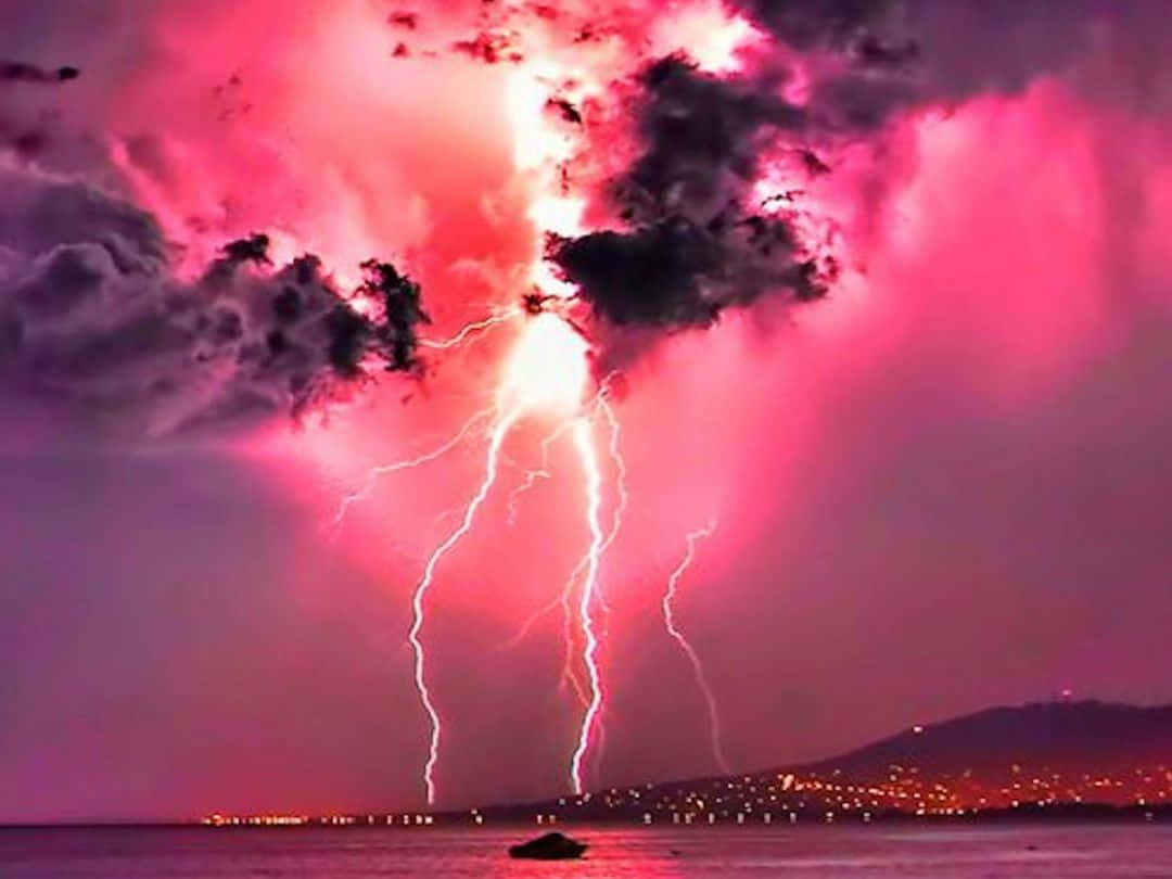 Stormy 桌布 壁紙 — 一場戲劇性的粉紅色雷暴照亮了夜晚的海岸城市，生動的電光劃破天空。