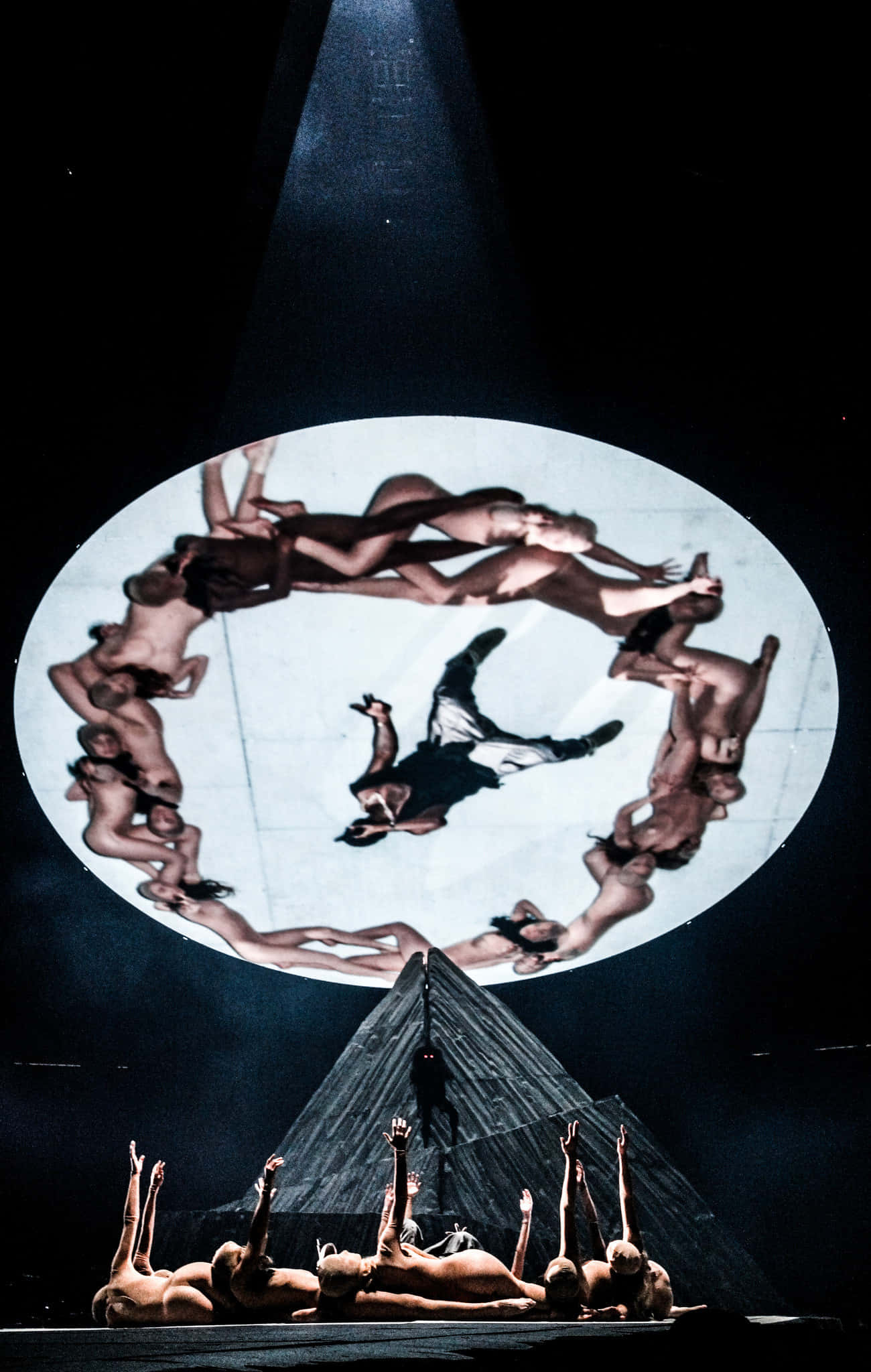Kanye West Yeezus 桌布 壁紙 — 一場戲劇性的舞台表演，舞者在聚光燈下圍繞中心人物形成圓圈。