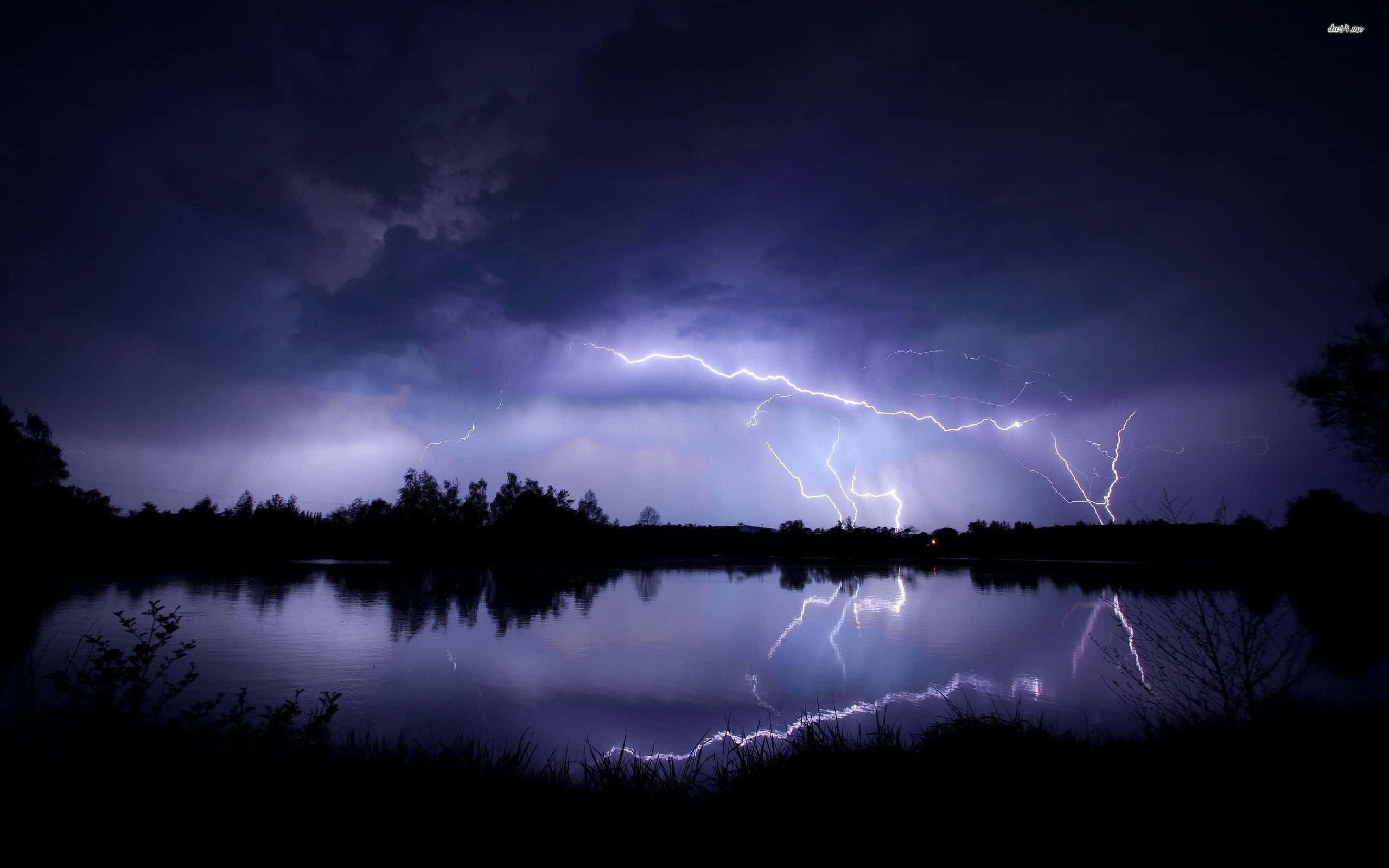 Cool Lightning 桌布 壁紙 — 一場戲劇性的雷暴照亮了夜晚的黑暗湖泊，紫色和白色的閃電在水中反射出鮮明的倒影。