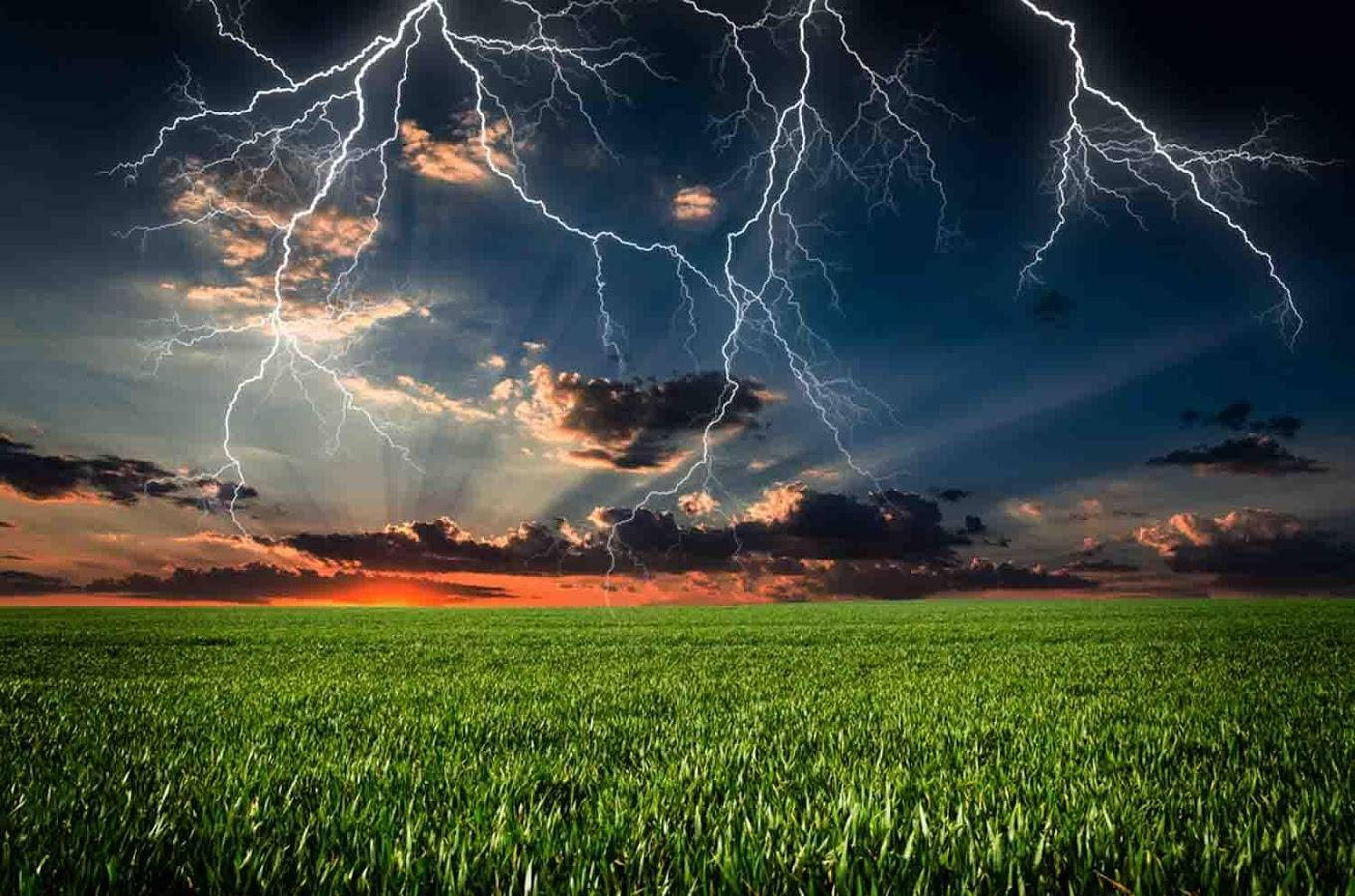 閃電 桌布 壁紙 — 一場戲劇性的雷暴照亮了日落時分廣闊的綠色田野，耀眼的光芒穿透烏雲。