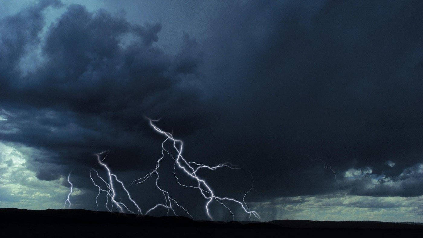 Storm 桌布 壁紙 — 一場戲劇性的雷暴照亮了黑暗的暴風雲，在剪影般的地平線上，鋸齒狀的閃電擊中大地。