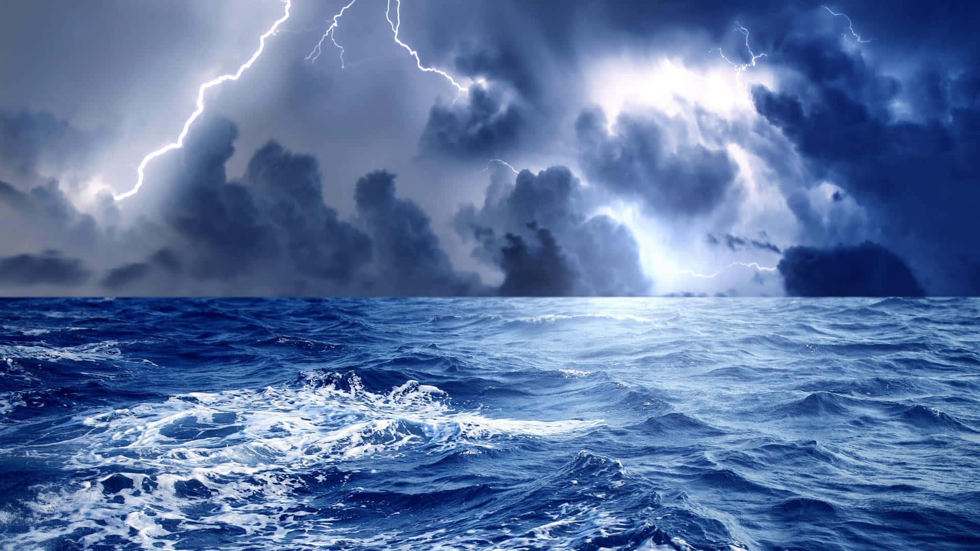 Ocean Storm 桌布 壁紙 — 一場戲劇性的風暴在翻騰的海洋上肆虐，生動的閃電照亮了烏雲和泡沫般的波浪。
