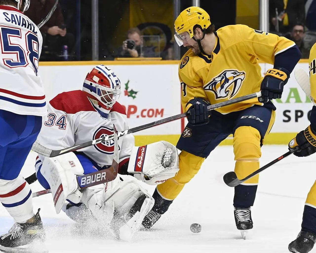 運動 桌布 壁紙 — 一場激烈的NHL比賽中，一位身穿黃色球衣的納什維爾掠奪者球員與身穿白色的蒙特婁加拿大人隊守門員在球門附近爭奪，冰球飛近球門。
