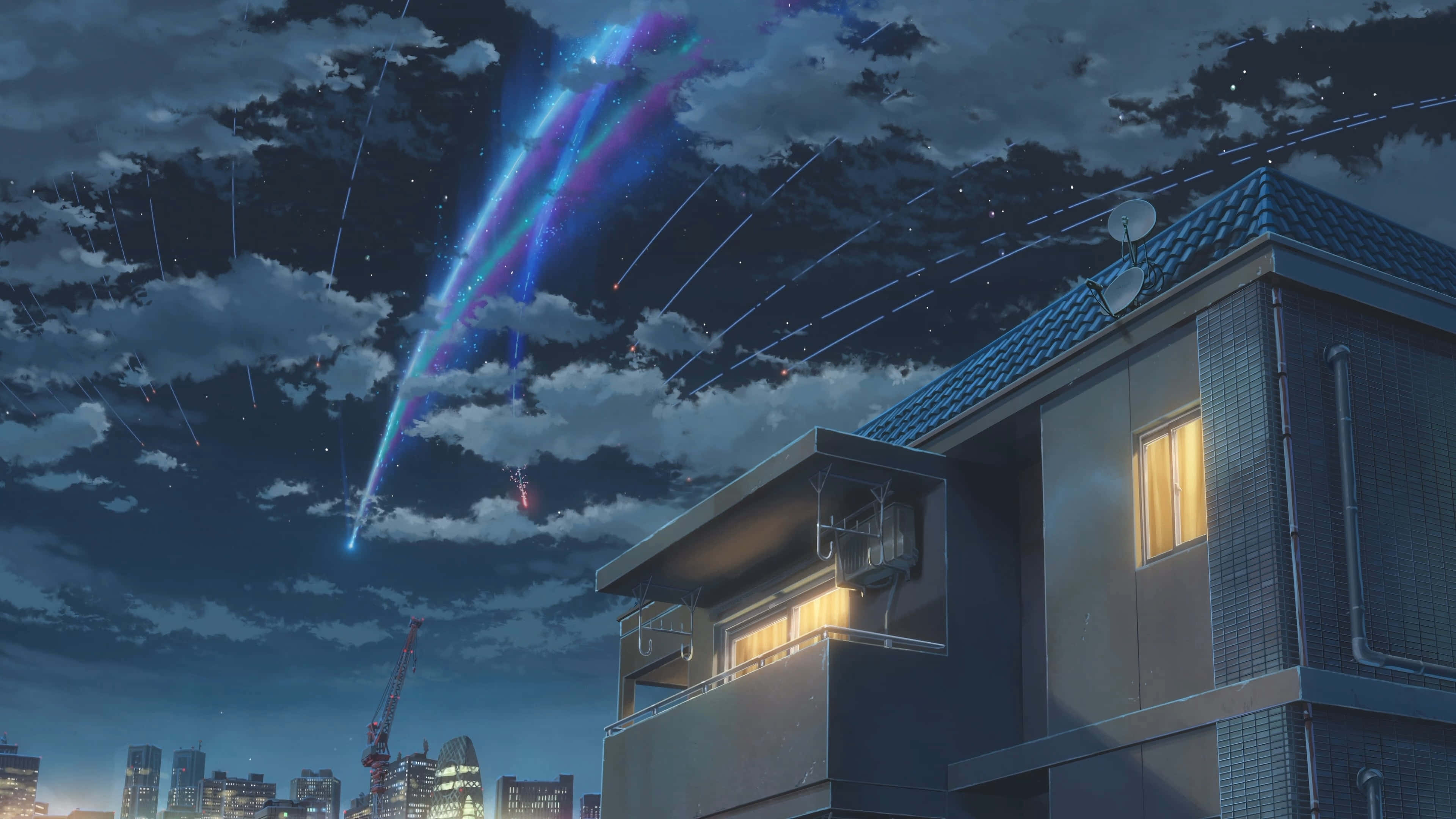 新海誠 桌布 壁紙 — 一場發光的宇宙流星雨劃過多雲的夜空，下方是寧靜的住宅樓宇，窗戶透出溫暖的燈光。