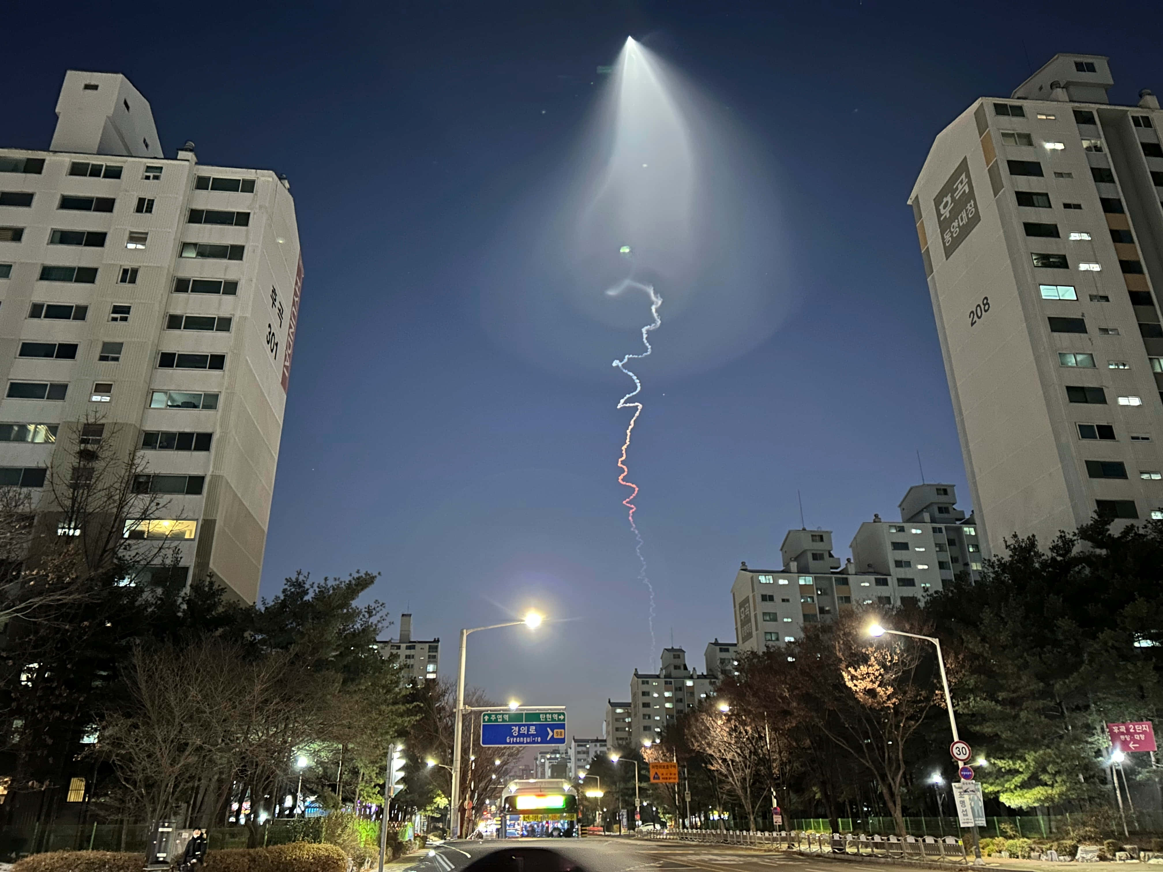 幽浮 桌布 壁紙 — 一場耀眼的燈光秀在高聳的公寓大樓之間垂直劃過城市夜空。