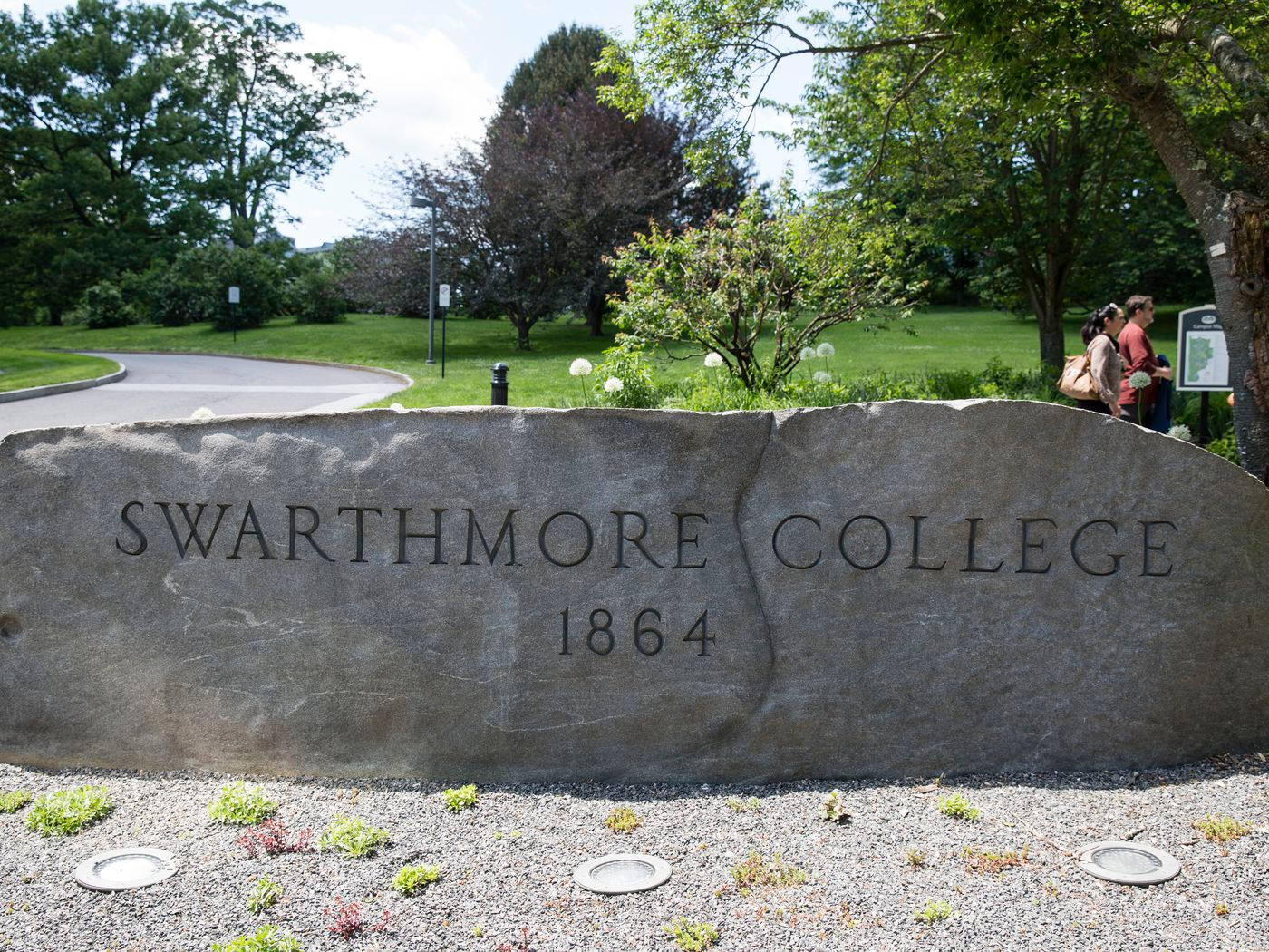 學校 桌布 壁紙 — 一塊 Swarthmore College 1864 的大型石牌矗立在陽光普照的校園花園中，附近有人走過。