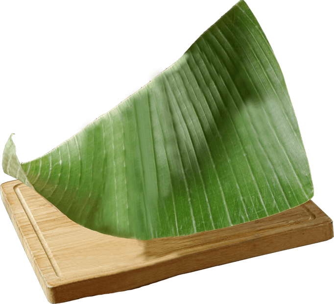 Daun 桌布 壁紙 — 一塊充滿活力的大綠香蕉葉斜放在淺色木砧板上，背景為黑色。